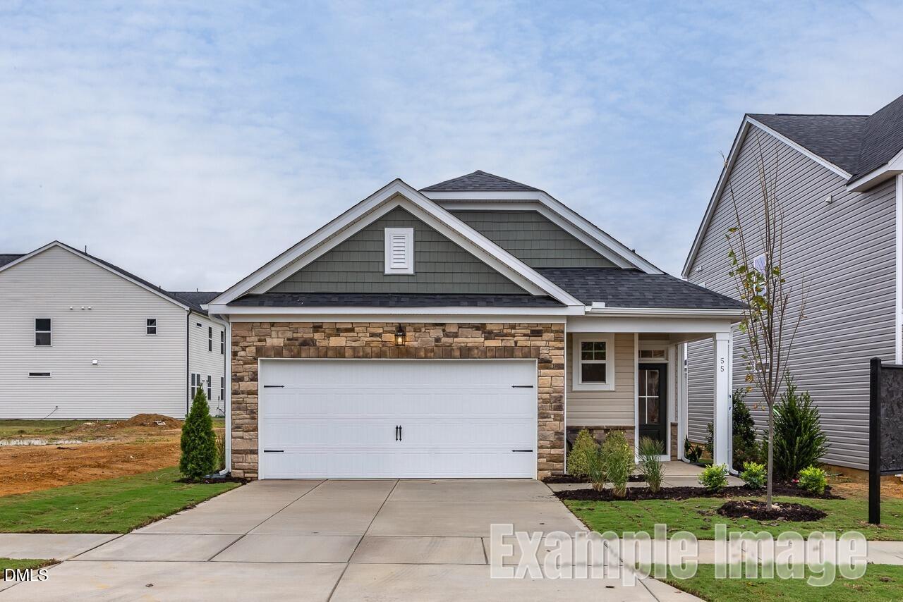 Modern 1-story 3-bedroom home with stone-accented 2-car garage, front porch, and landscaping in Gregory Village, Lillington, North Carolina