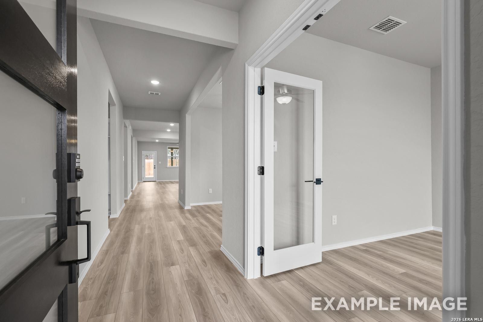 Bright entryway with French door study and luxury wood-look flooring in The Glenwood E home at Royal Crest, San Antonio.