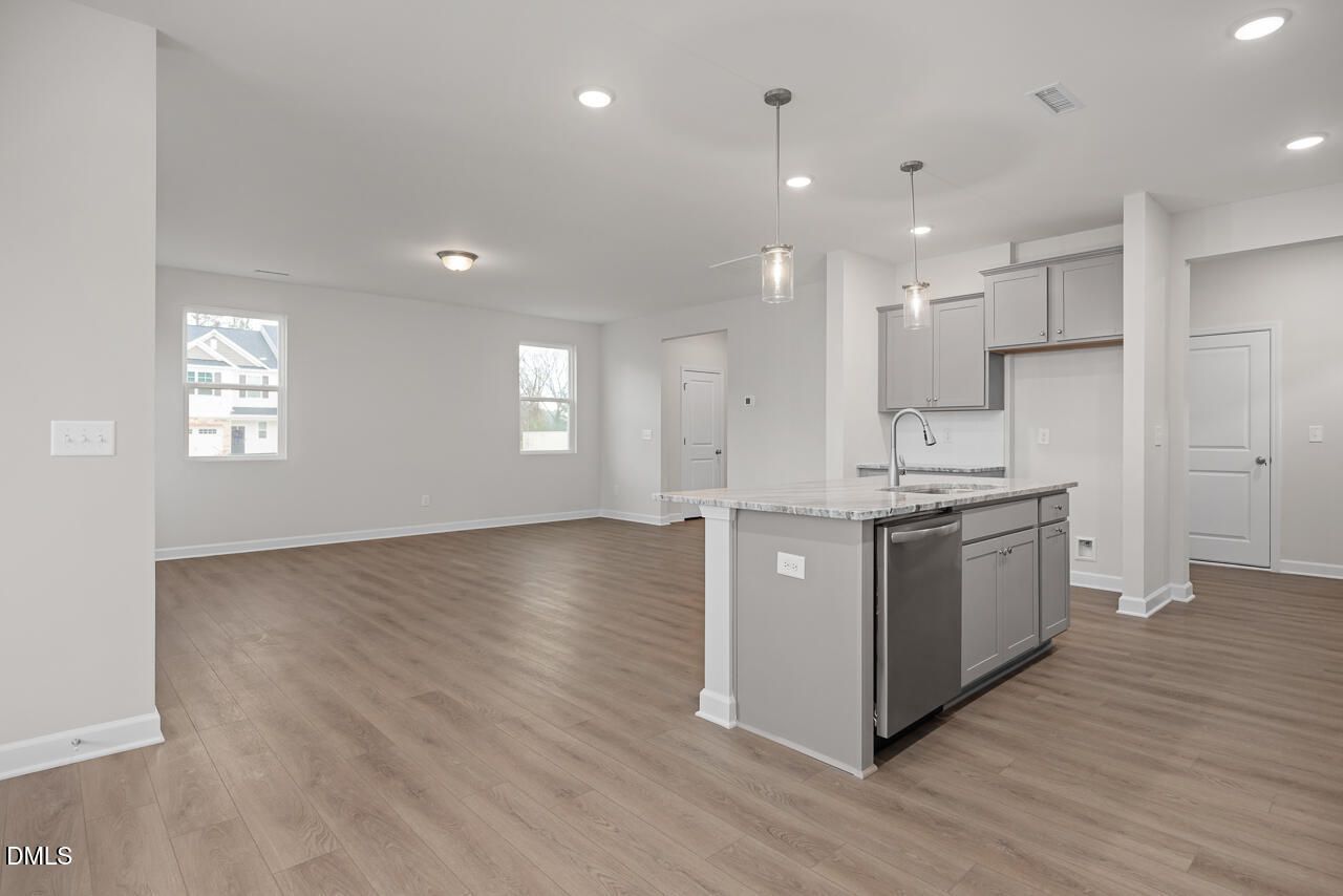 Modern open-concept kitchen with white shaker cabinets, quartz island, and stainless dishwasher in The Gavin B, Lillington, NC