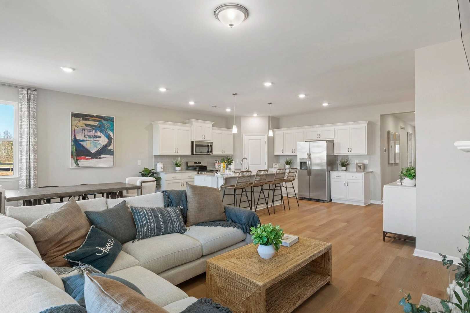 Spacious open-concept living room and kitchen in Bailey Park, Fayetteville TN with hardwood floors, white cabinets, sectional sofa, and fireplace