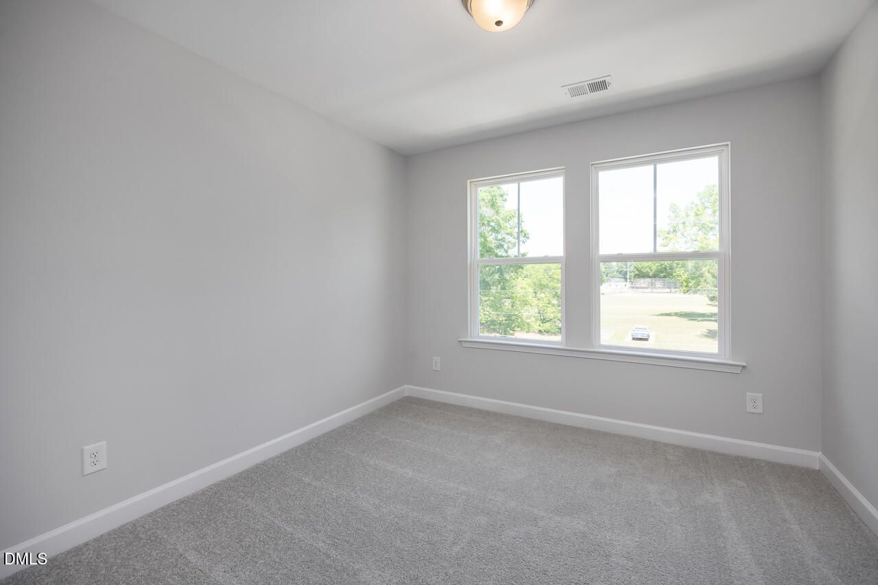 Bright bedroom with neutral gray paint and plush carpeting in The Mitchell floor plan at Camden Park, Knightdale, NC.