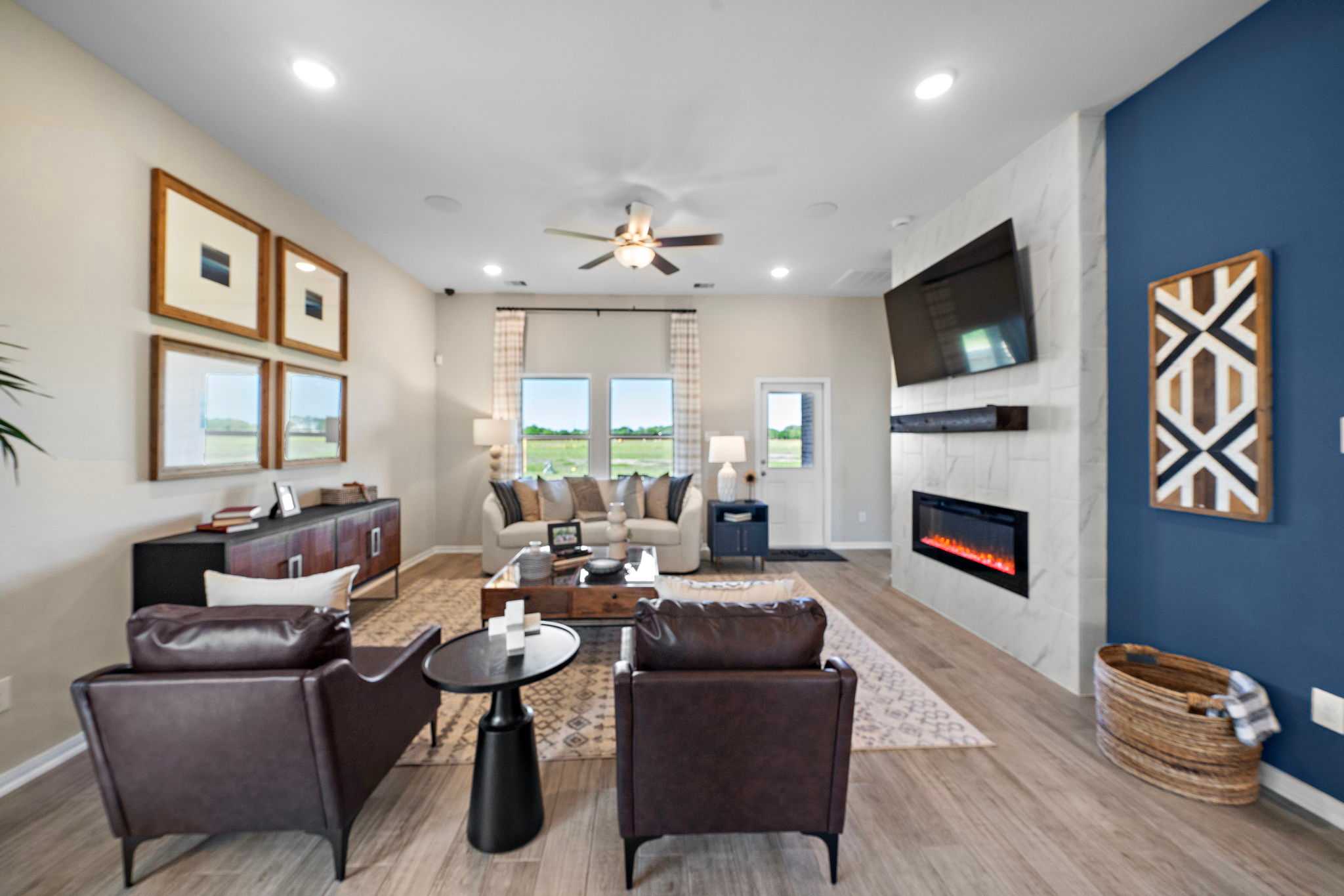 Open-concept living room in Emberly Beasley Texas featuring linear gas fireplace, beige sofa, leather armchairs, and hardwood floors