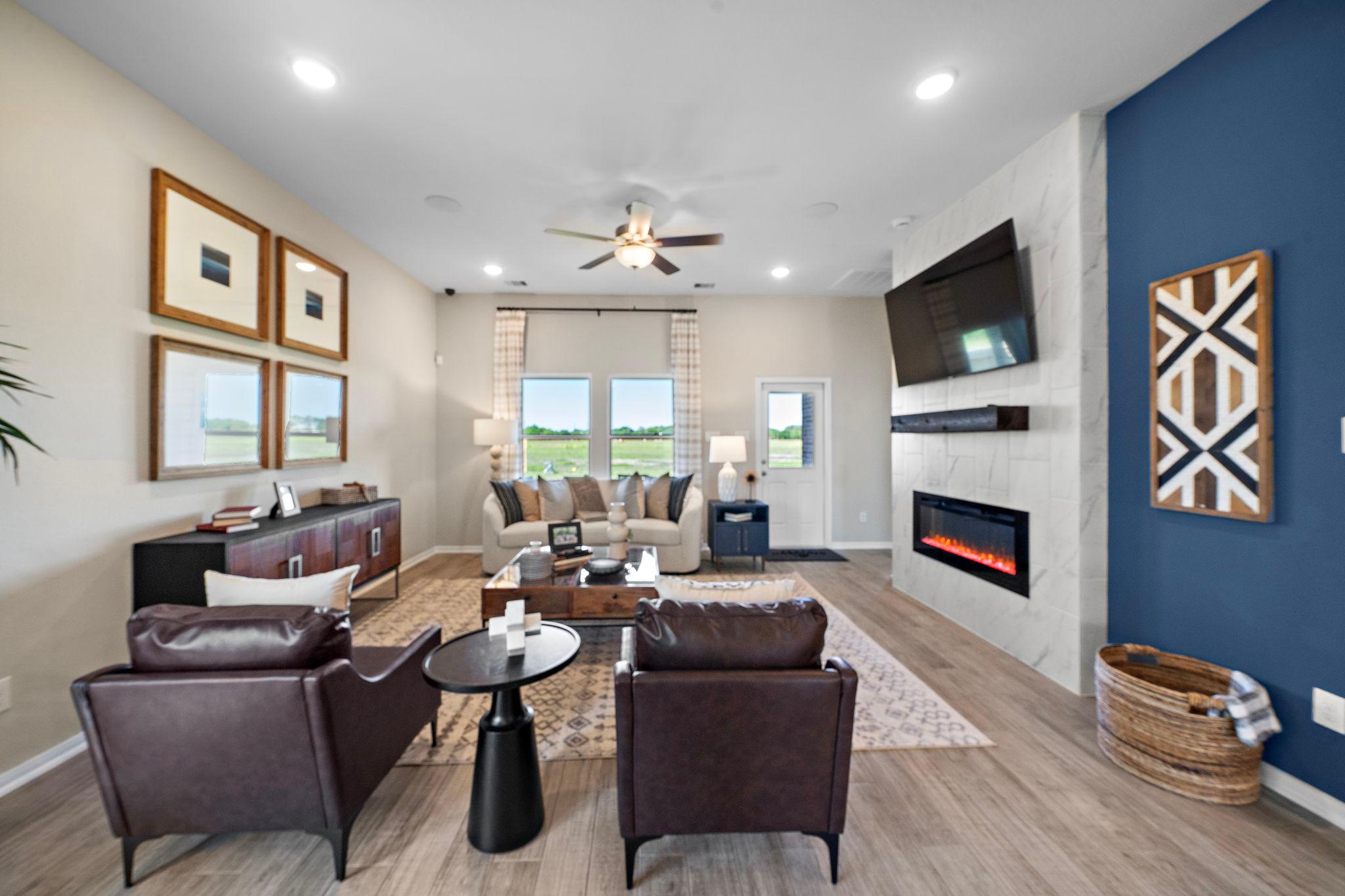Open-concept living room in Emberly Beasley Texas featuring linear gas fireplace, beige sofa, leather armchairs, and hardwood floors