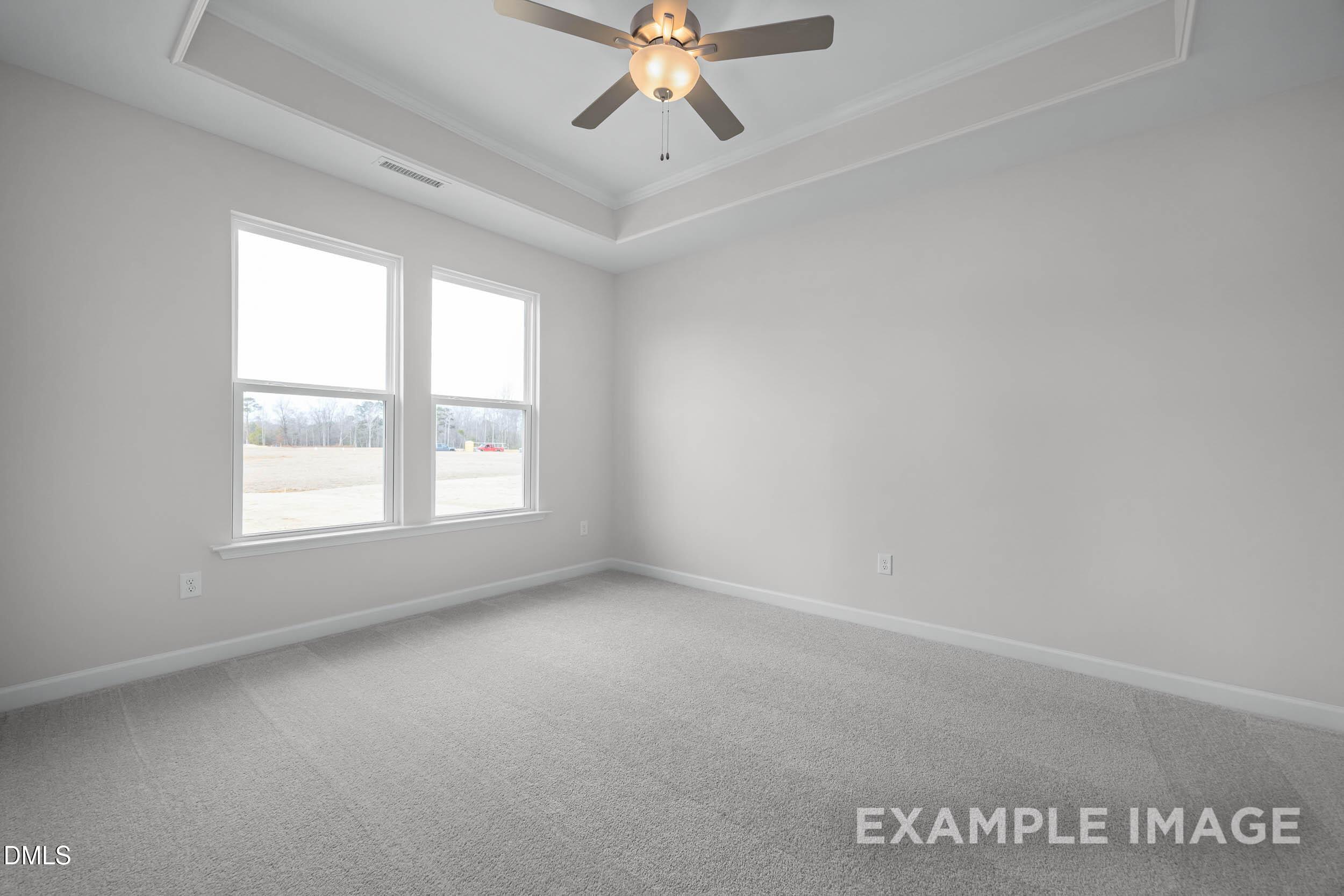 Bright bedroom with tray ceiling and ceiling fan in The Franklin C floor plan at Retreat at North Main, Lillington, NC.
