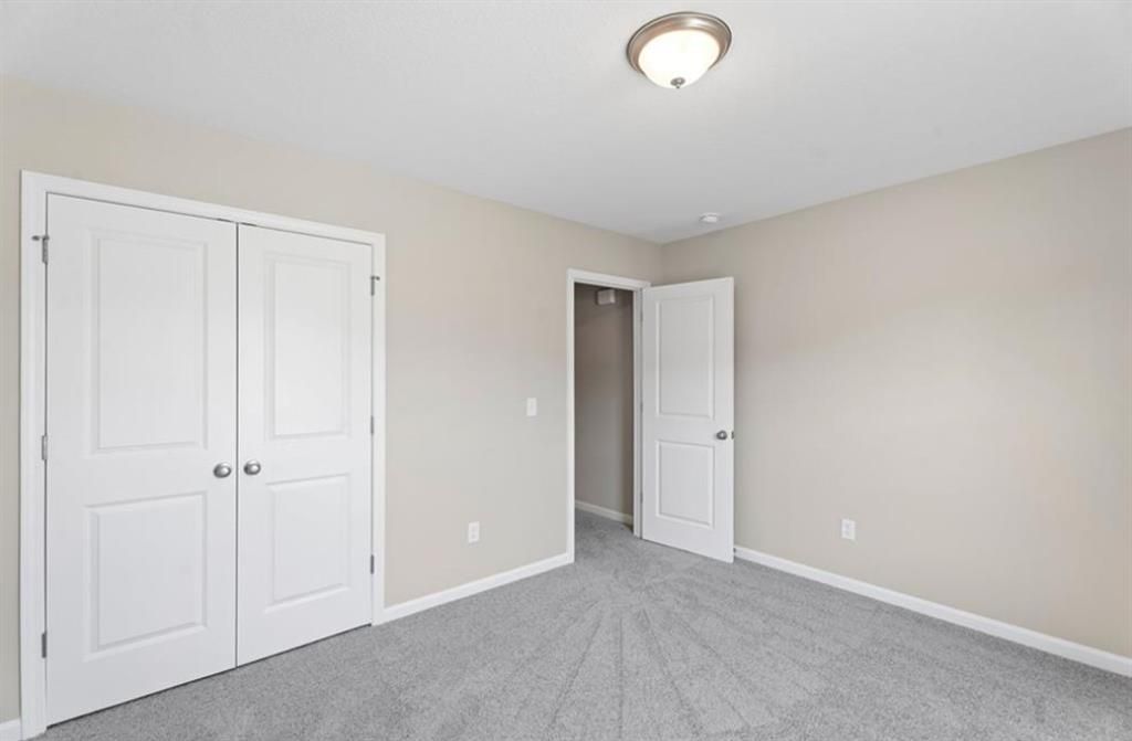 Beige bedroom with gray carpet, white double-door closet, and adjacent bath door in Davidson Homes The Washington, Phenix City, Alabama