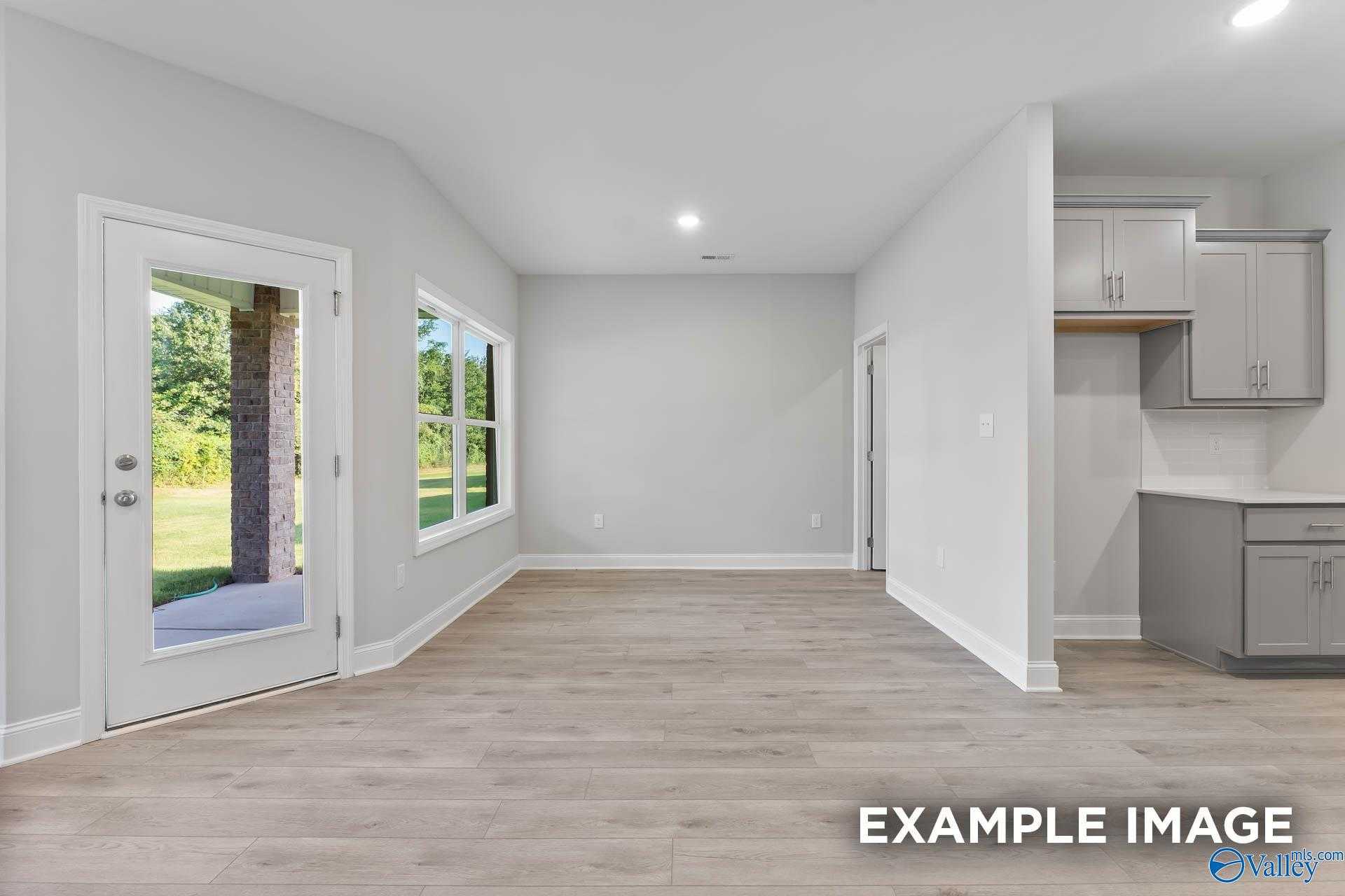 Bright open-concept living area with hardwood floors, French doors to backyard, and adjacent kitchen in Davidson Homes The Daphne C, New Market, AL