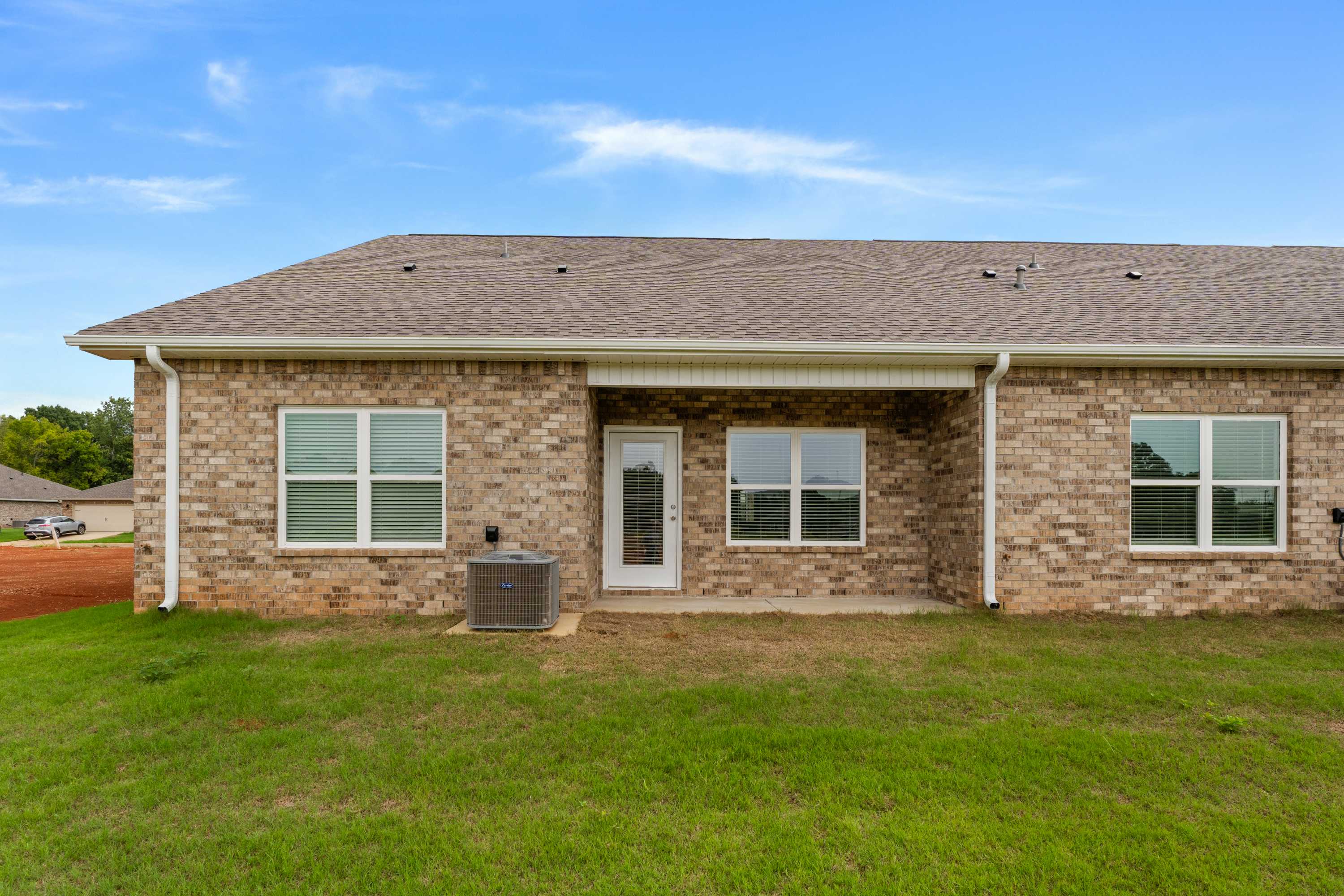Brick home rear exterior at The Retreat at Hollon Meadow in Decatur Alabama with covered patio, large windows, and grassy yard