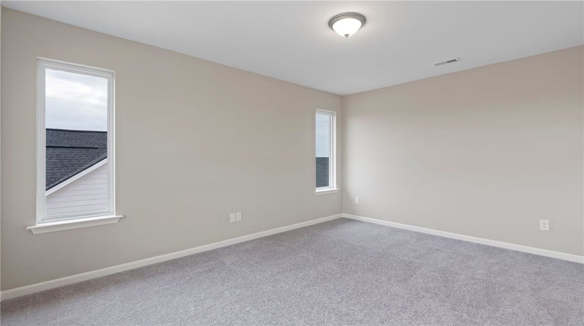 Empty beige bedroom with large window overlooking roof, carpet floor in Evermore Homes The Stella D, Cusseta, Alabama