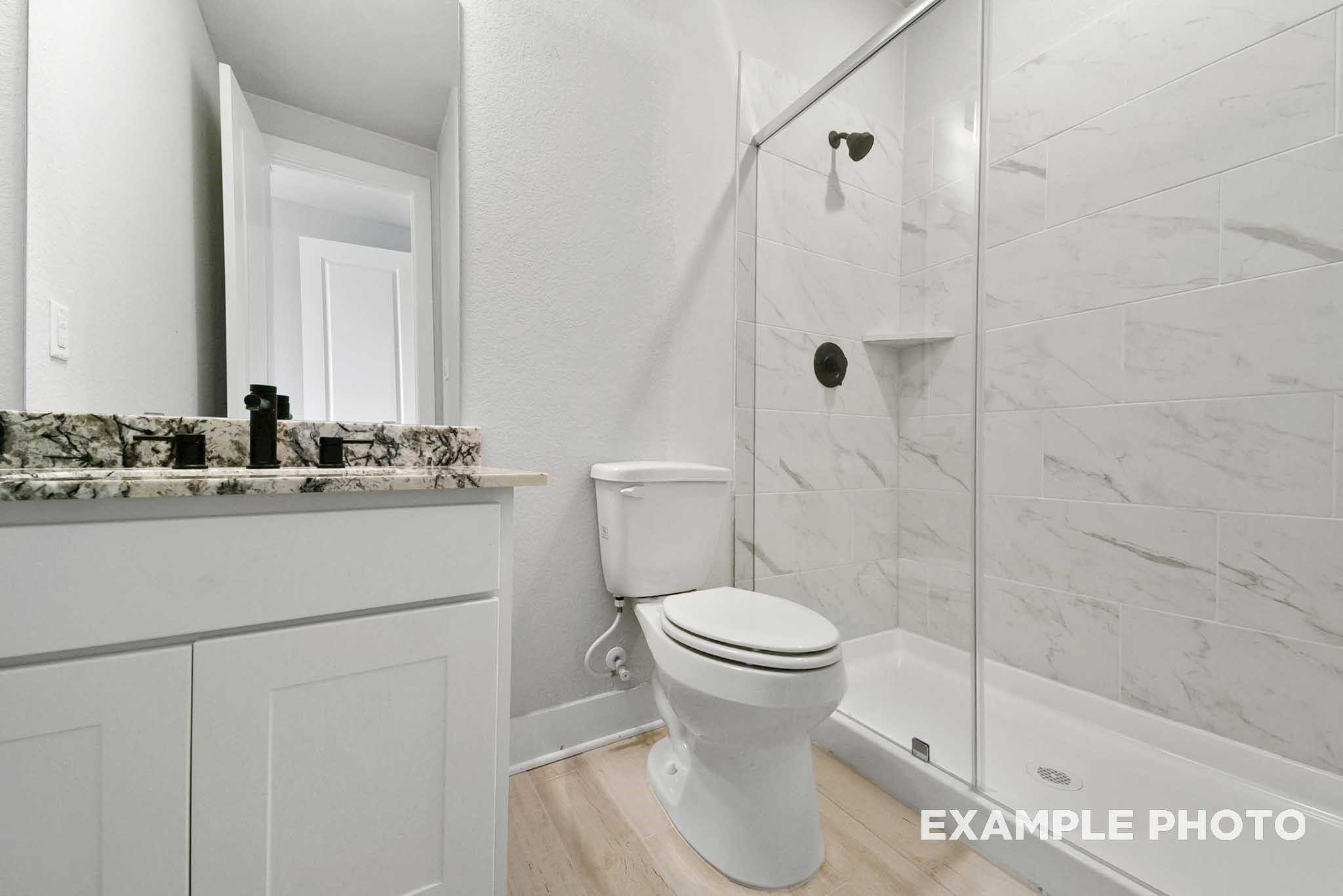 Modern guest bathroom featuring white subway tile shower, quartz vanity, and glass enclosure in Davidson Homes The George A, Texas City
