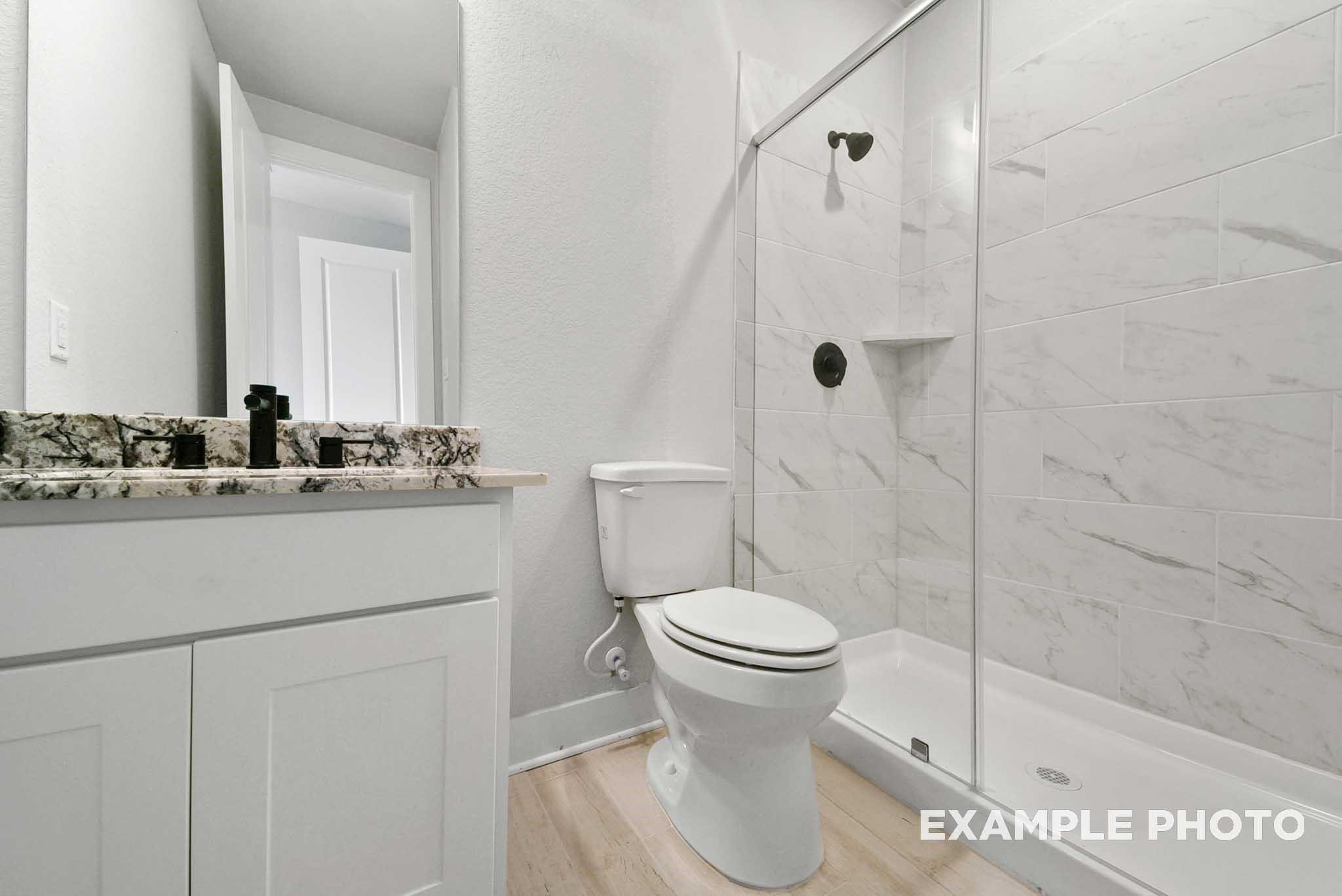 Modern guest bathroom featuring white vanity, granite countertop, glass shower, and subway tile in Davidson Homes The George A, Lago Mar, Texas City
