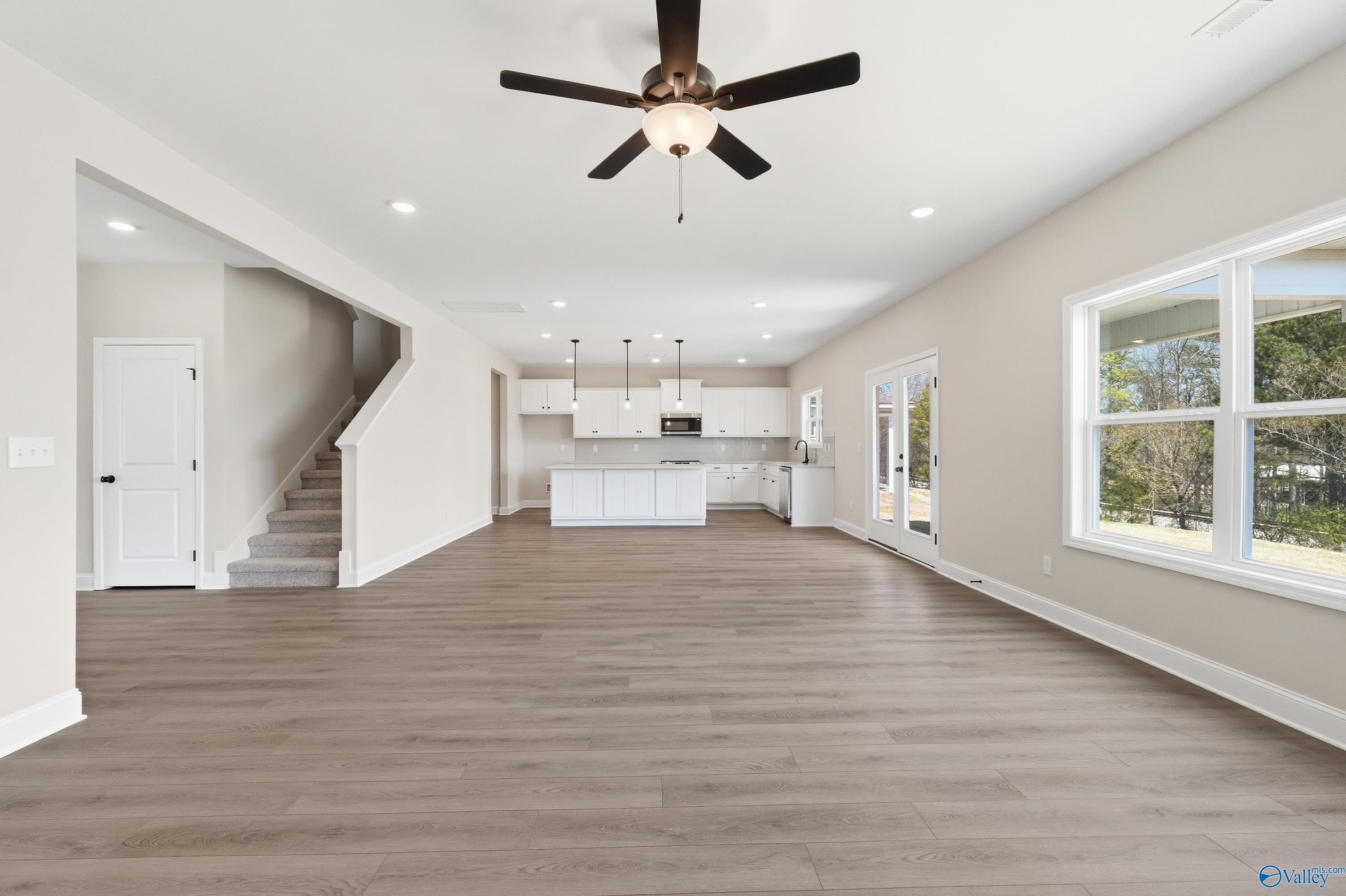 Open-concept living area with hardwood floors, ceiling fan, and white kitchen cabinets in Davidson Homes Chelsea D, Cullman, AL