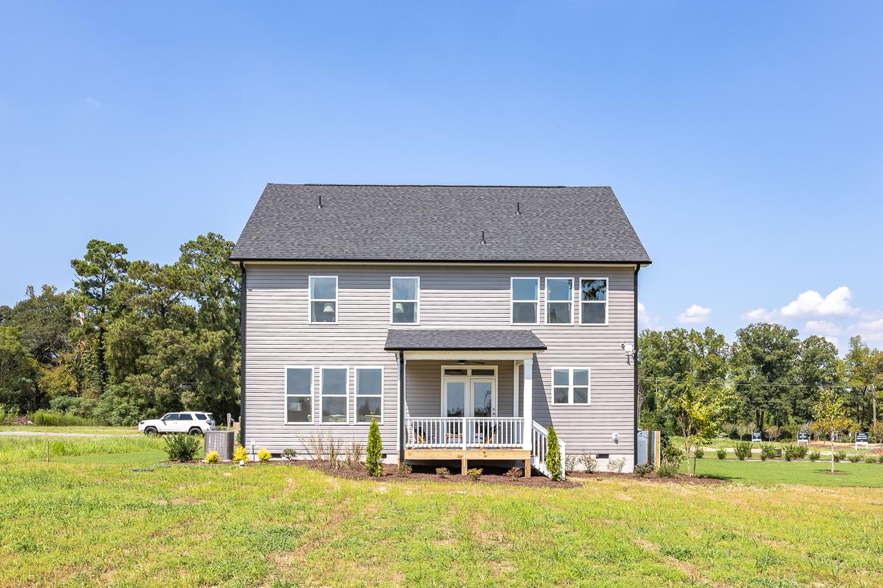 Two-story gray home exterior at Wellers Knoll in Lillington NC with covered front porch deck and wooded backdrop