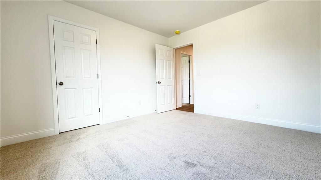Bright, carpeted secondary bedroom with white doors in The Hickory C floor plan at Wehunt Meadows, Hoschton, Georgia.