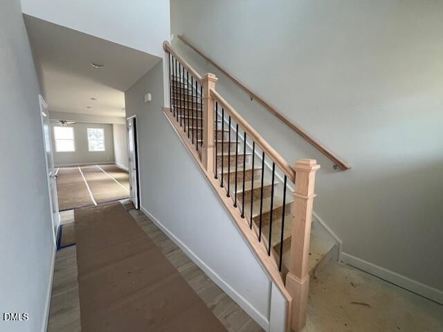 Elegant oak staircase with black iron balusters in bright hallway of 4-bedroom two-story home, The Adalynn B, Lillington, NC