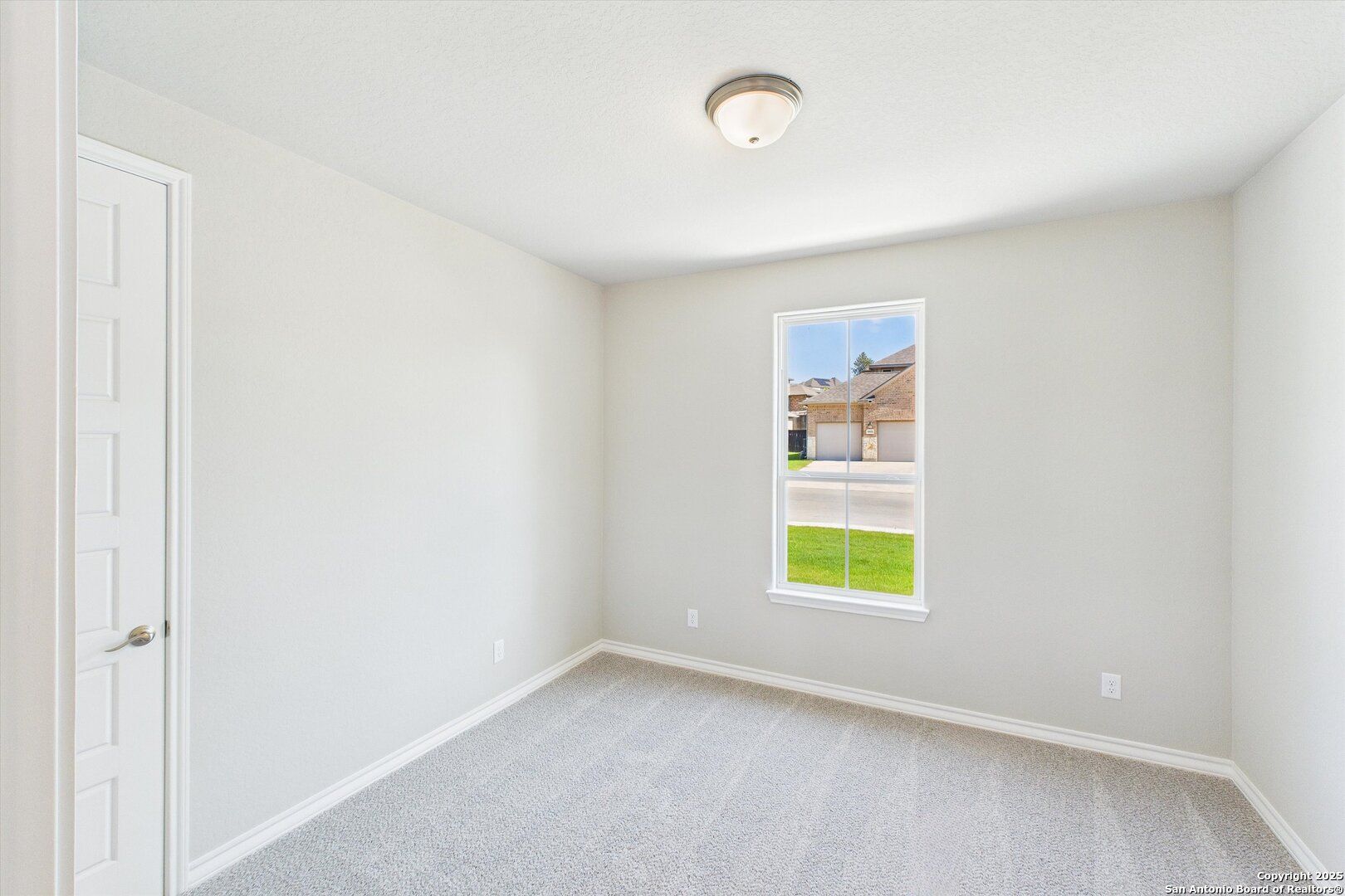 Bright secondary bedroom with neutral walls, beige carpet, and window overlooking green lawn in Davidson Homes The Jennings H, Ladera, San Antonio