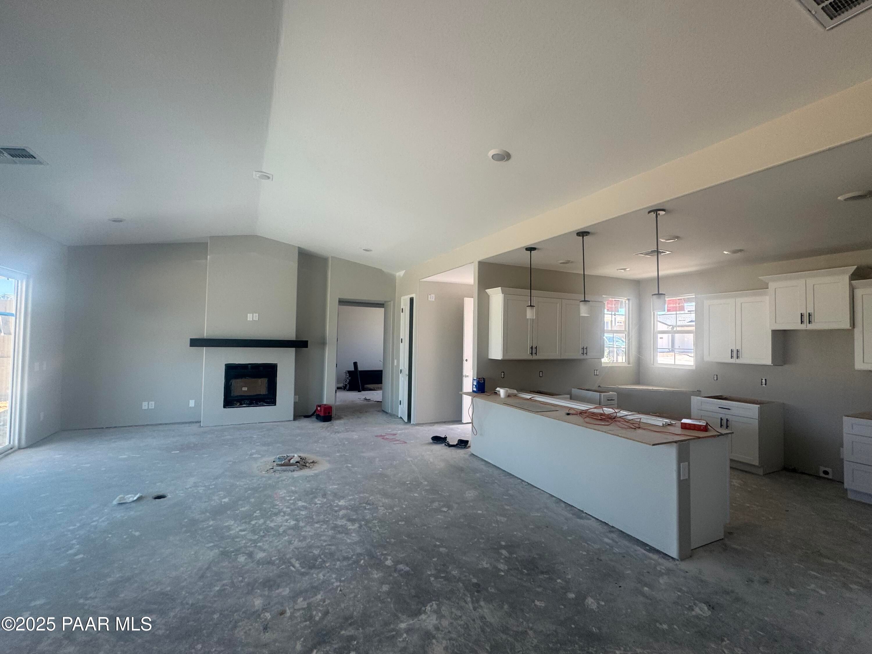 Open-concept kitchen and living room with white shaker cabinets, large island, and linear gas fireplace in Davidson Homes The Daybreak E, Prescott AZ