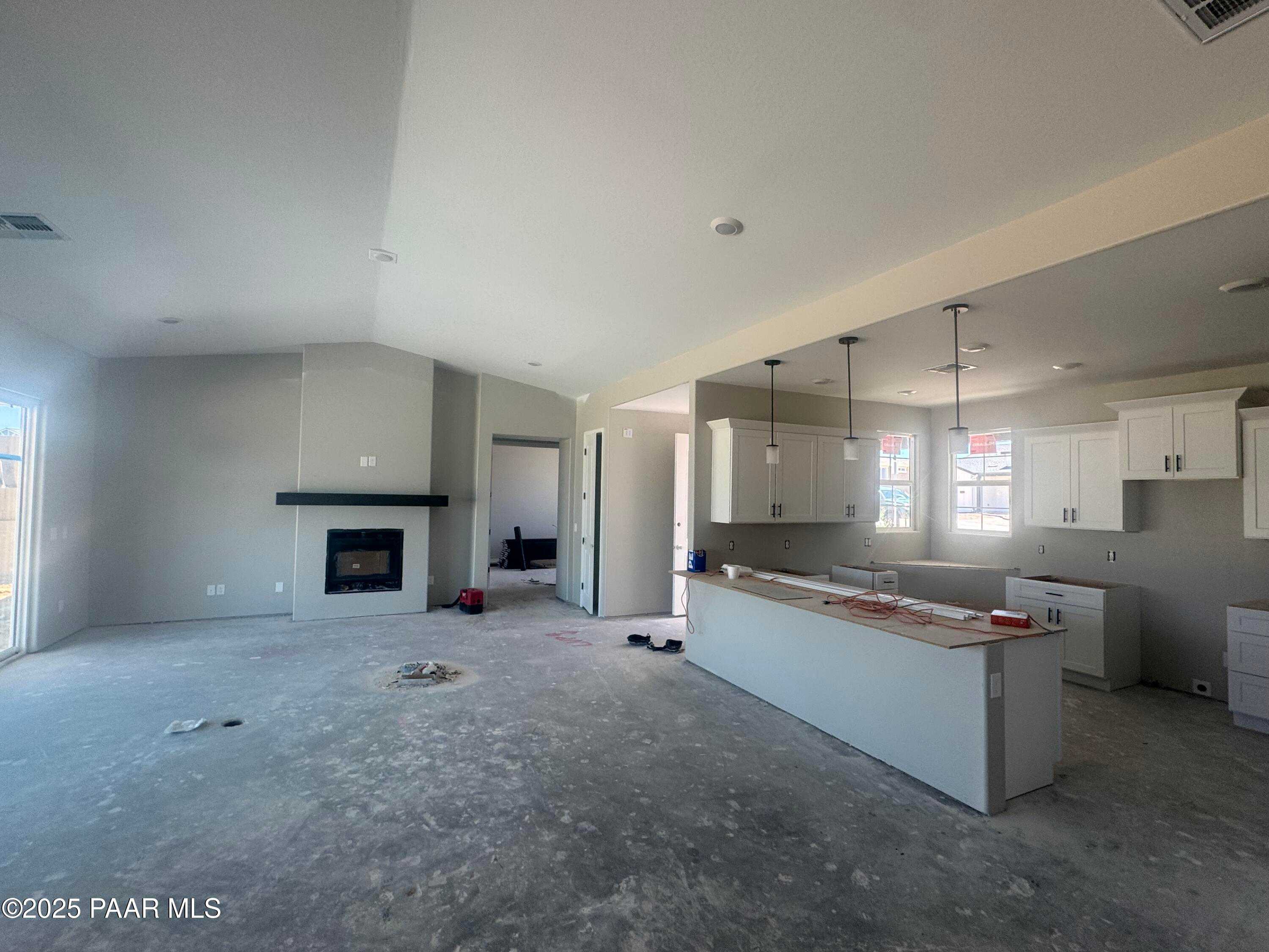Open-concept kitchen and living room with white shaker cabinets, large island, and linear gas fireplace in Davidson Homes The Daybreak E, Prescott AZ