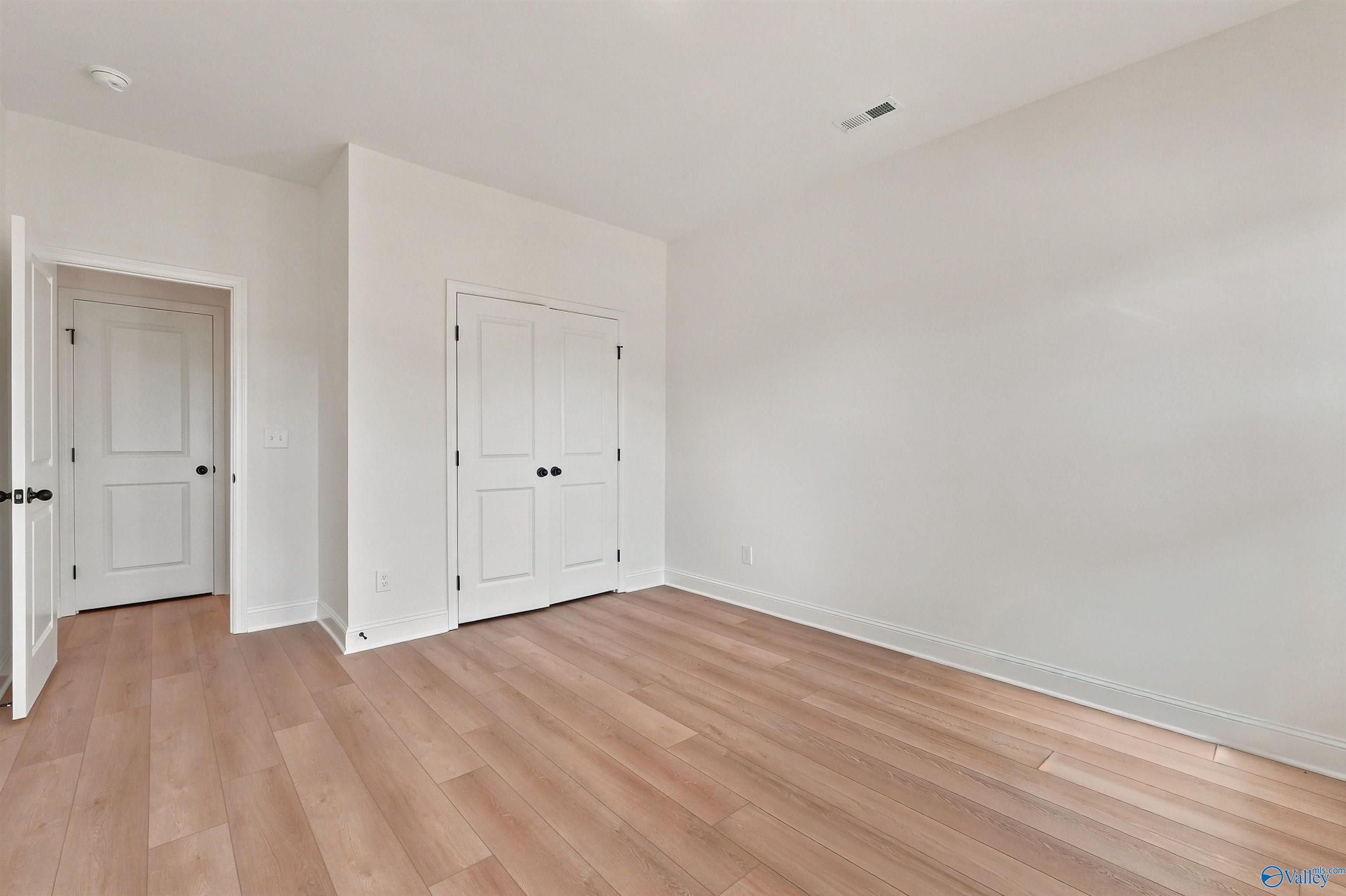 Bright bedroom with light wood flooring and double closet doors in The Chelsea C floor plan, Creek Grove, New Market, AL.