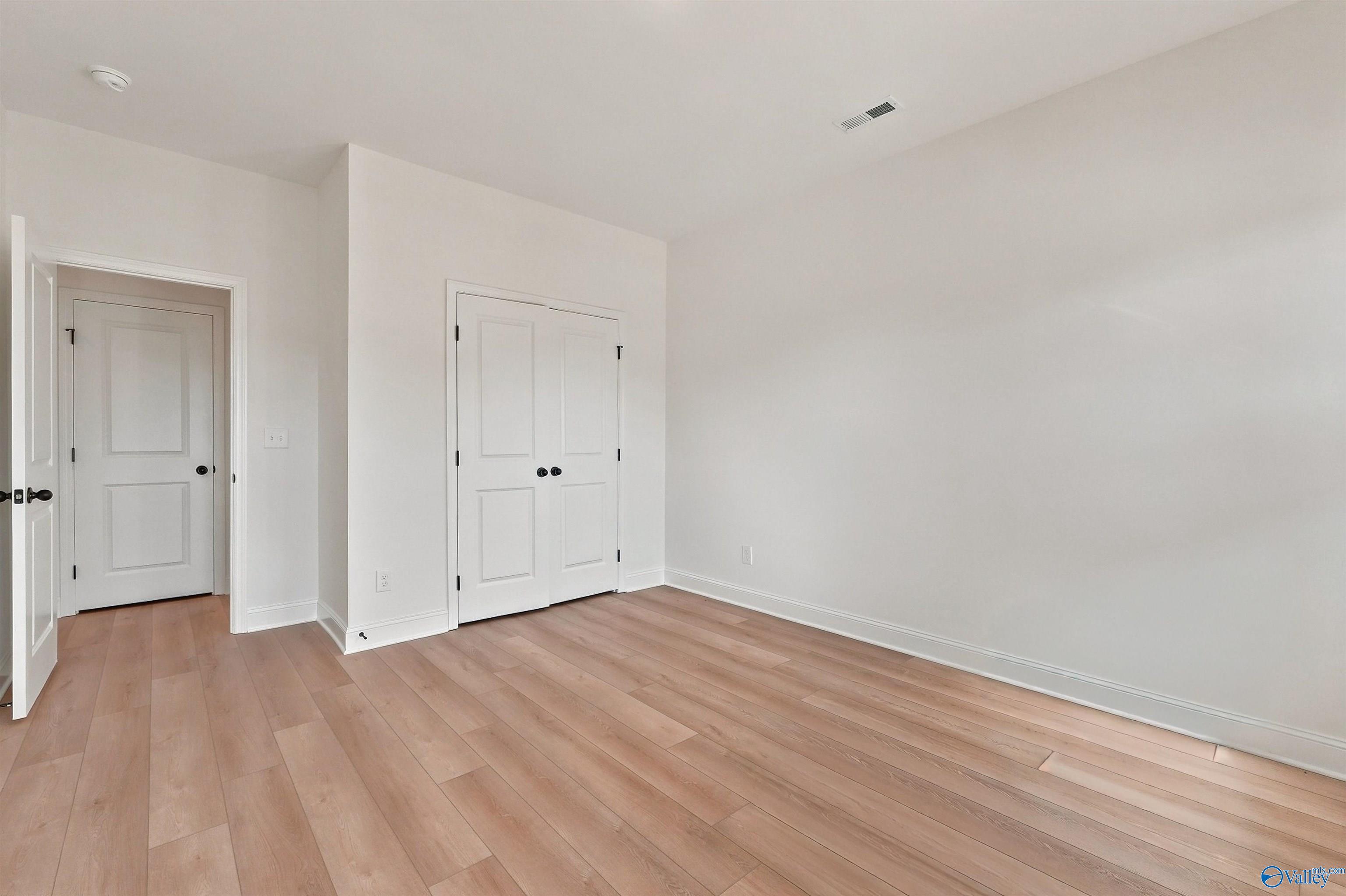 Bright bedroom with light wood flooring and double closet doors in The Chelsea C floor plan, Creek Grove, New Market, AL.