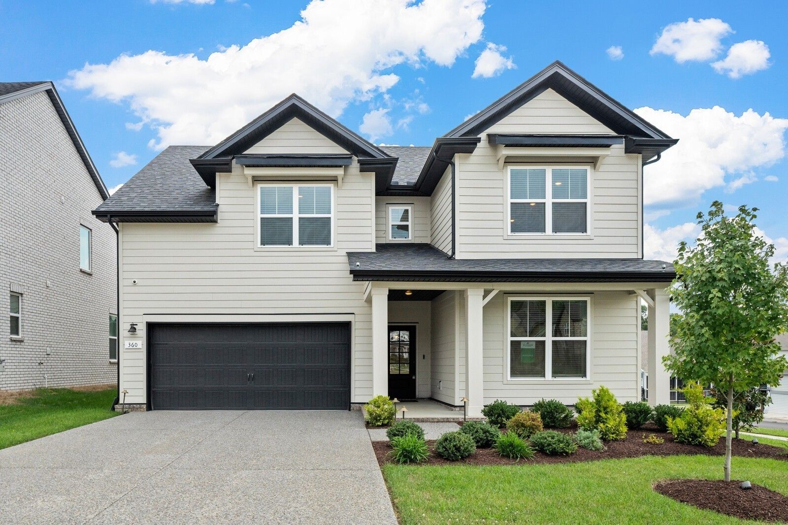 Modern two-story Ridgeport home exterior with beige siding, black 2-car garage, covered porch, and landscaped yard in Carellton, Gallatin, Tennessee