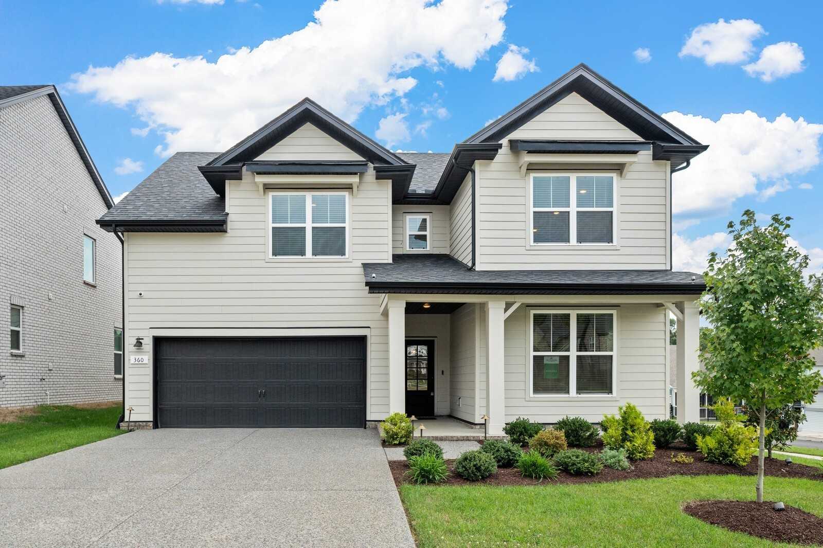 Modern two-story Ridgeport home exterior with beige siding, black 2-car garage, covered porch, and landscaped yard in Carellton, Gallatin, Tennessee