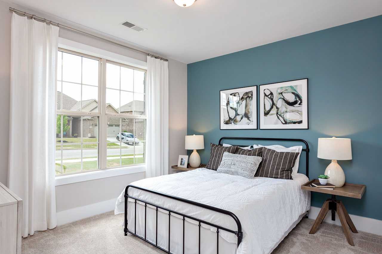 Serene secondary bedroom in The Rockford by Davidson Homes: teal accent wall, black metal bed, large window with sheer curtains, abstract art