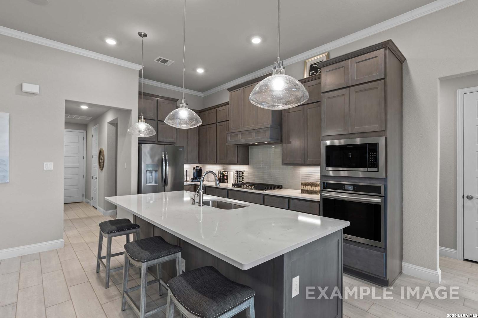 Modern kitchen with quartz island, grey cabinets, and stainless appliances in The Garner C plan at Potranco Oaks, TX.