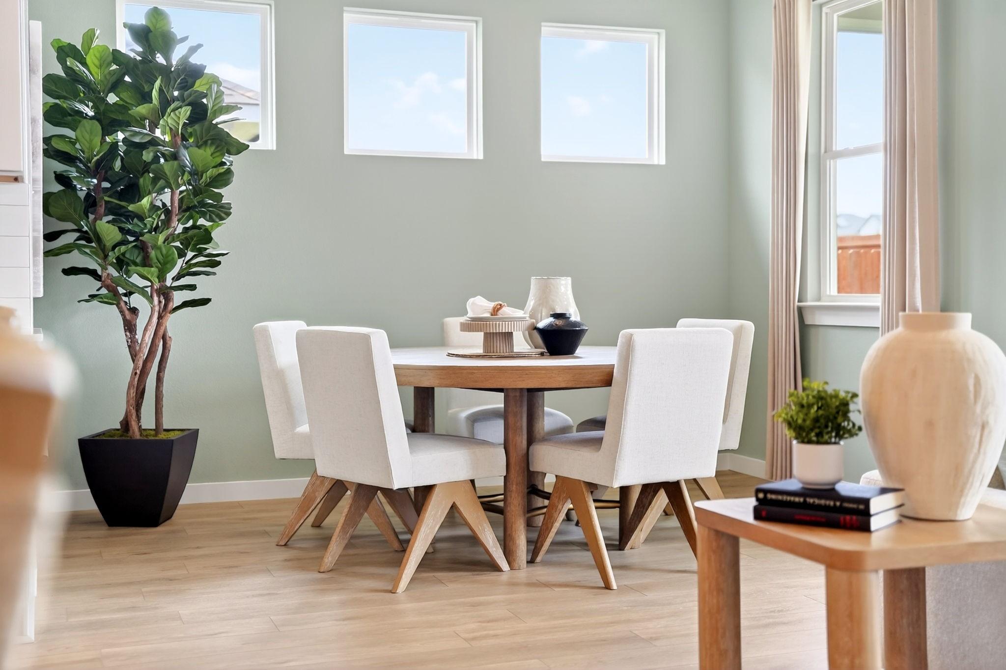 Bright dining area with round wood table and chairs in The Laurel M floor plan at Parks at Foster Crossing, Anna, Texas.