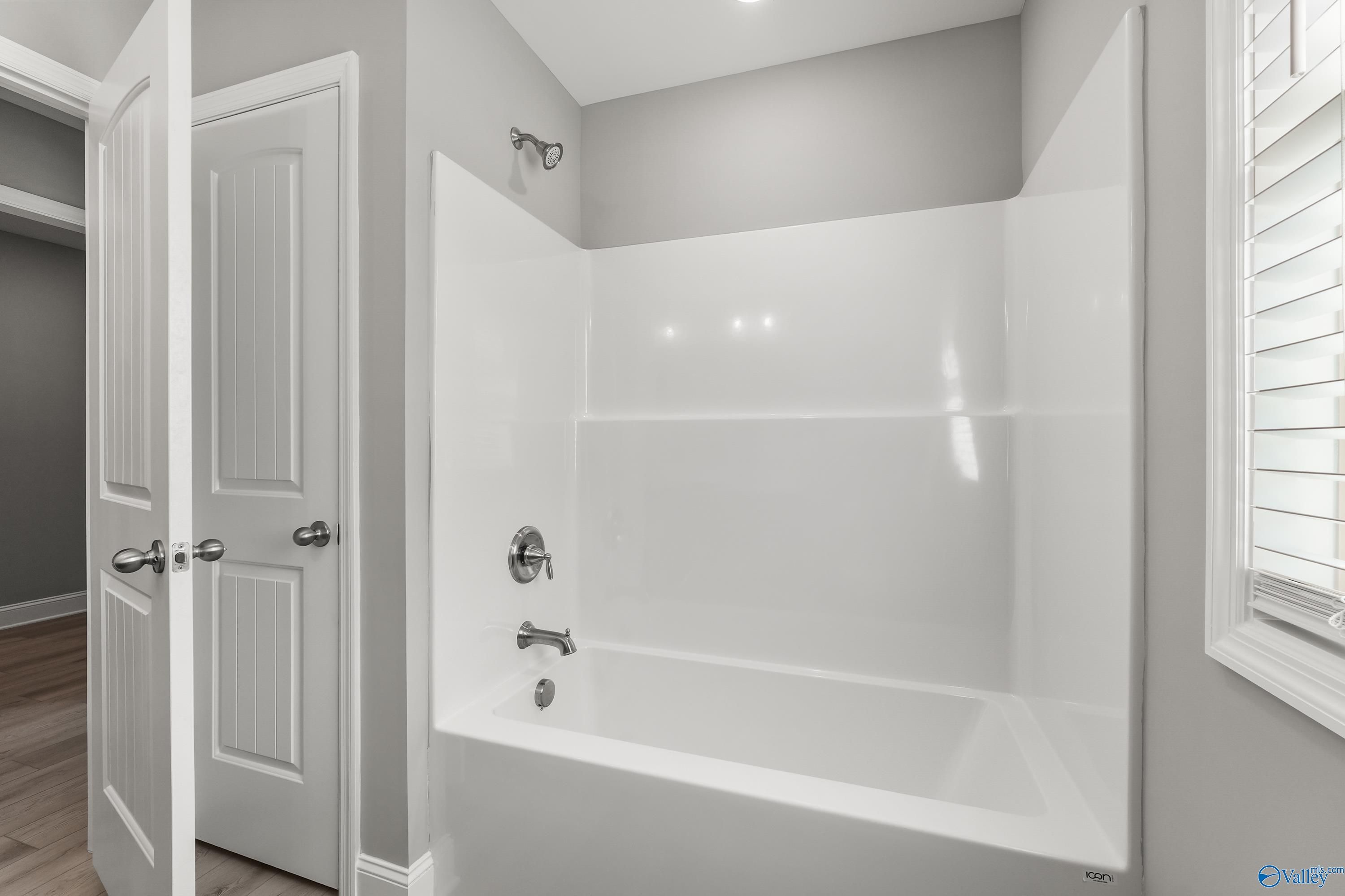 Modern bathroom with white tub, glass shower enclosure, gray walls in Davidson Homes The Everett B, Athens, Alabama