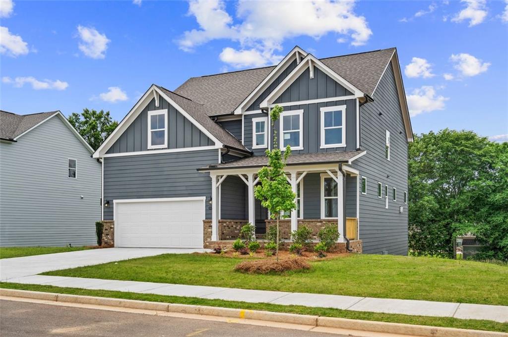 Two-story gray craftsman home with front porch, two-car garage, and landscaped yard, Davidson Homes The Hickory B in Wehunt Meadows, Hoschton, GA