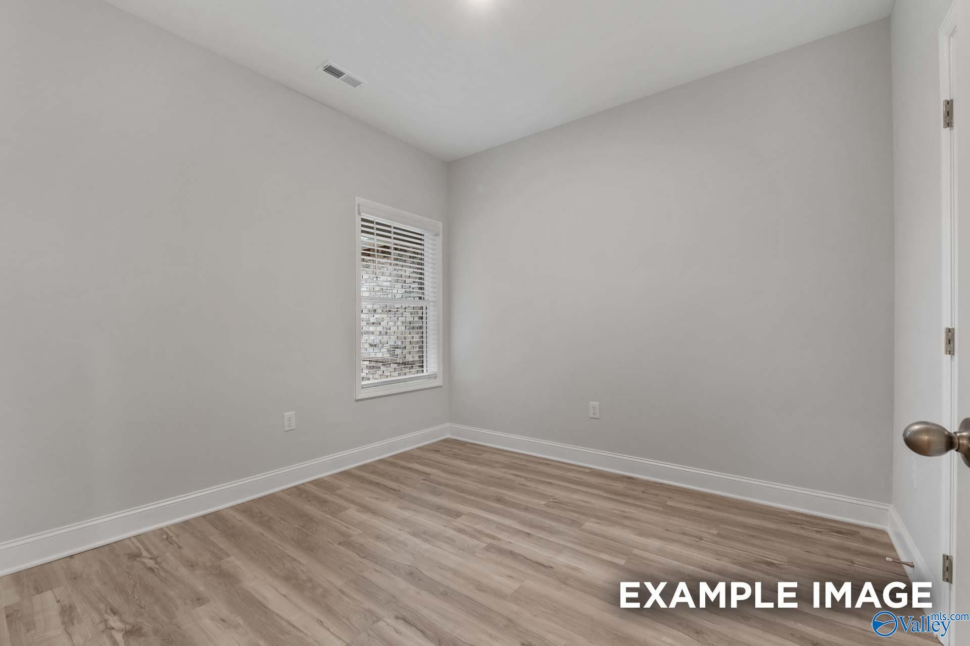 Cozy secondary bedroom with light gray walls, hardwood floors, and window blinds in Davidson Homes The Cumberland B, Decatur, Alabama