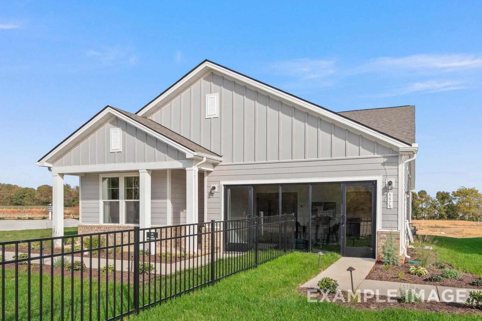 Modern gray single-story home with 2-car garage, covered porch, black fence, and landscaped yard in Sage Farms, White House, TN