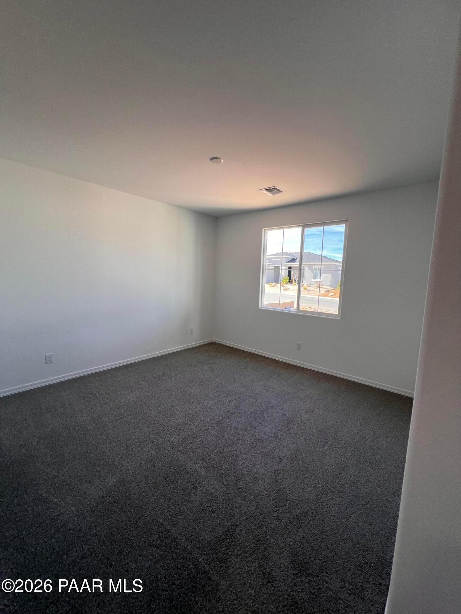 Bright empty bedroom with large window, gray carpet, and white walls in The Summit A home, Westwood, Prescott, Arizona