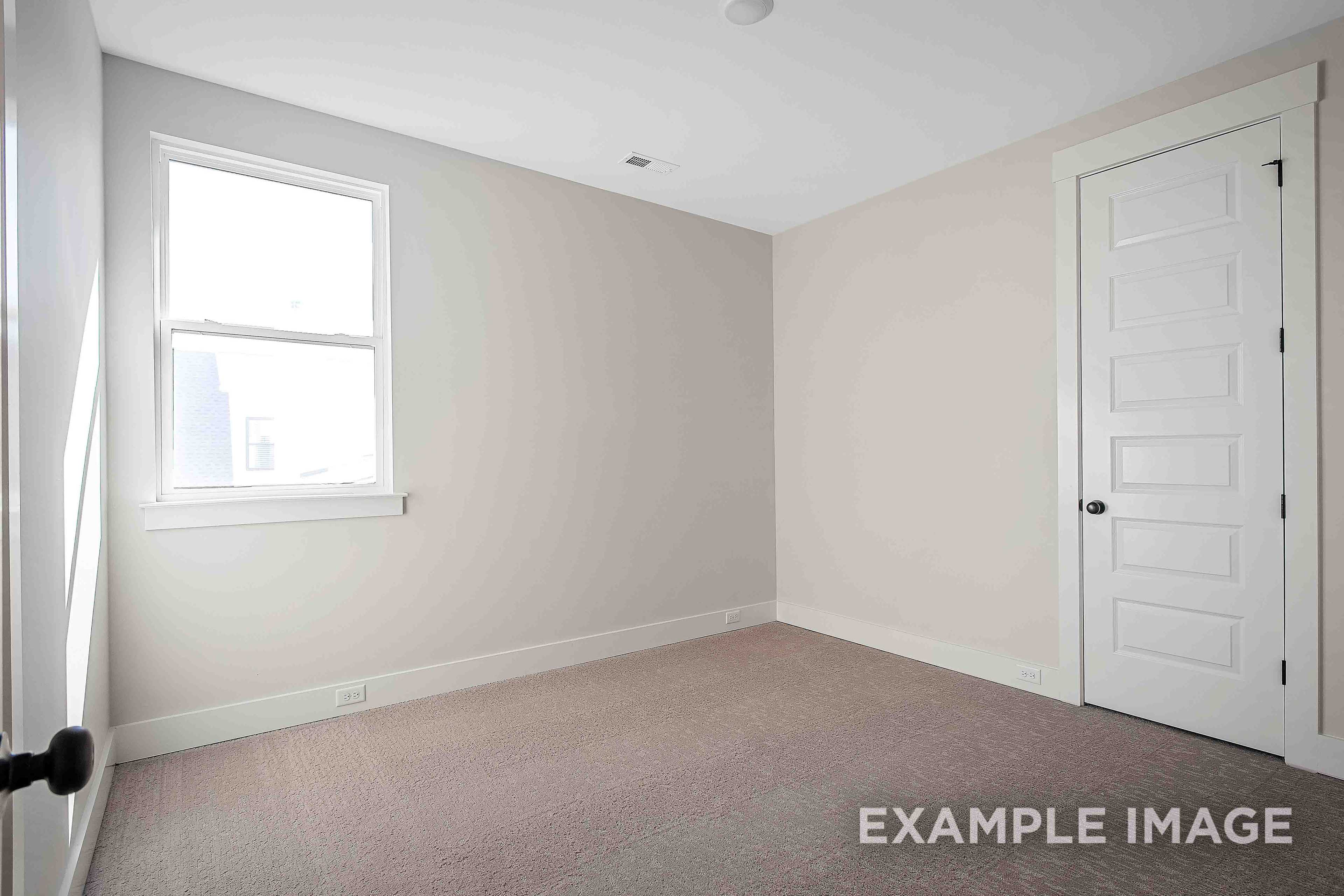 Spacious empty master bedroom in The Alston A featuring beige walls, large window, and carpeted floor