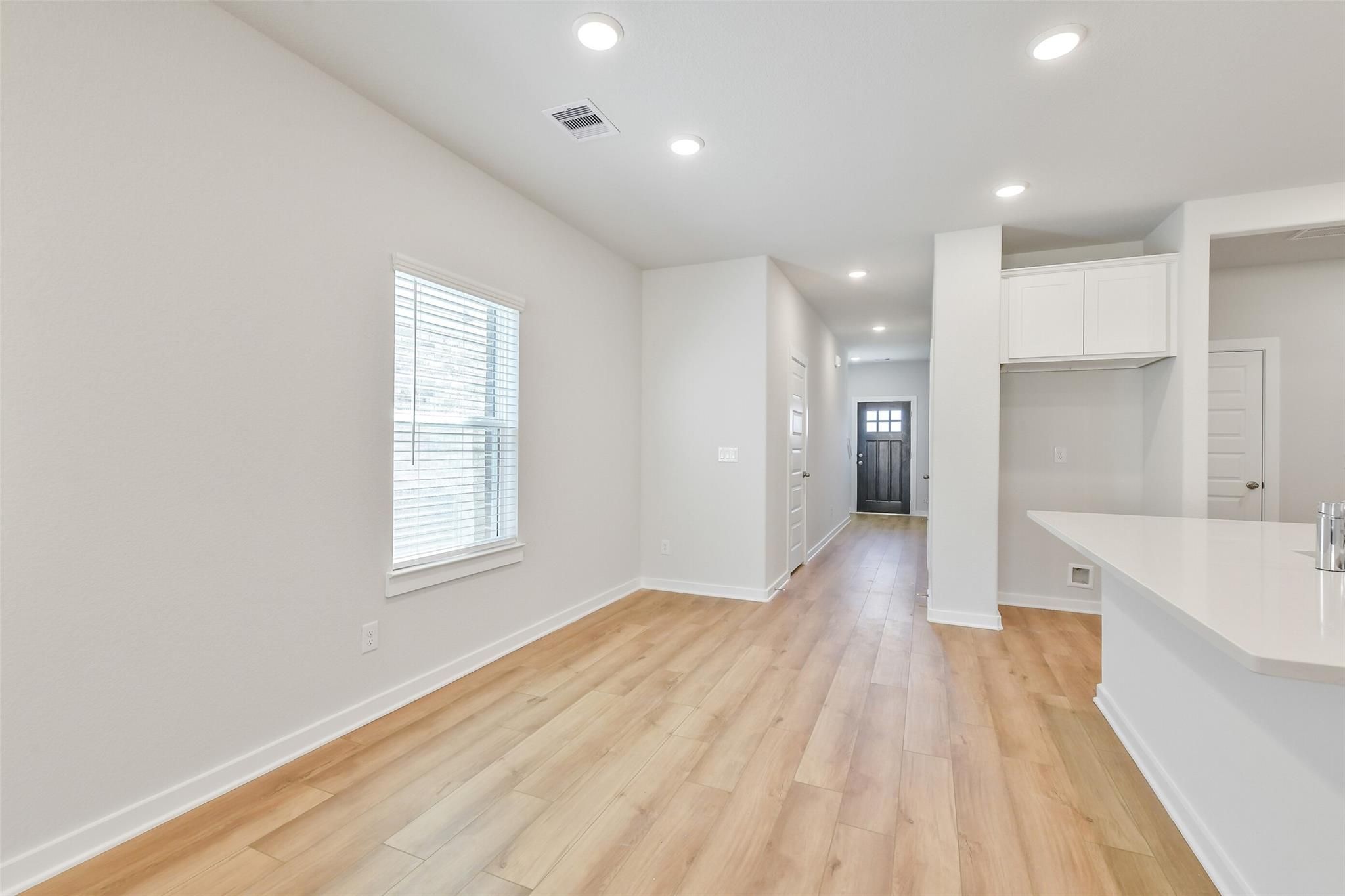 Bright hallway with light oak floors, white cabinets, quartz counter in Davidson Homes The Blanco E, Magnolia TX
