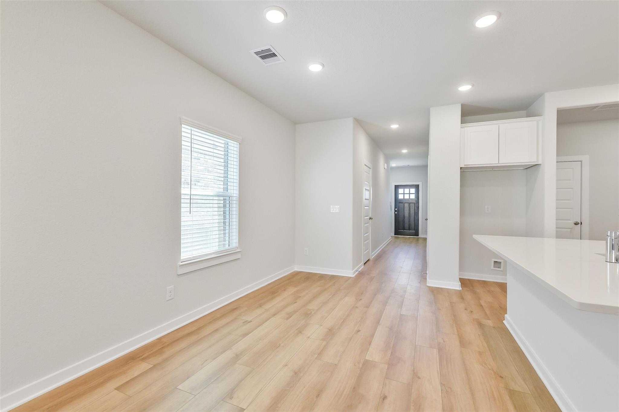 Bright hallway with light oak floors, white cabinets, quartz counter in Davidson Homes The Blanco E, Magnolia TX