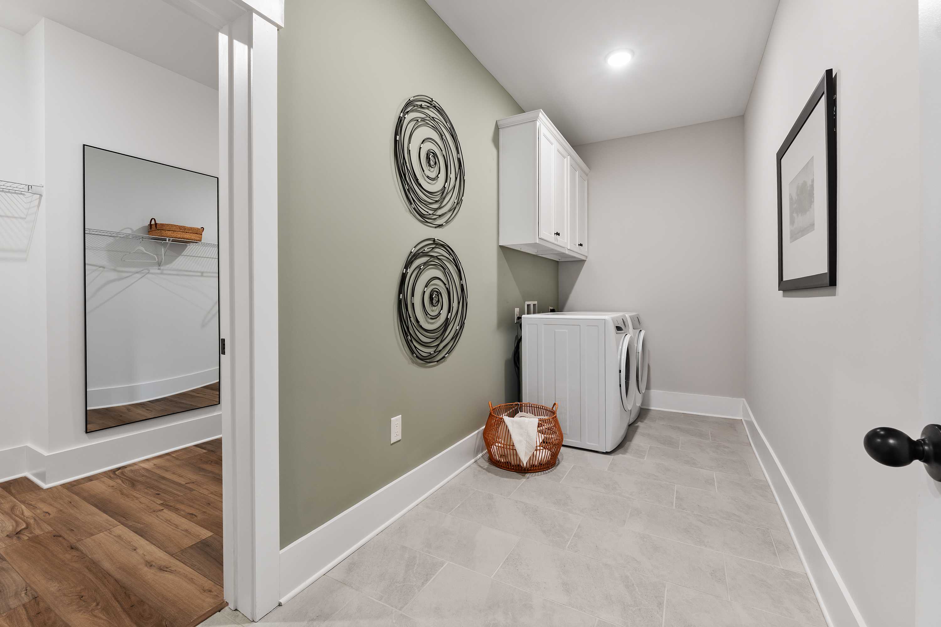 Spacious laundry room at River Road Estates in Decatur AL with white washer dryer, circular wall art, and built-in shelves