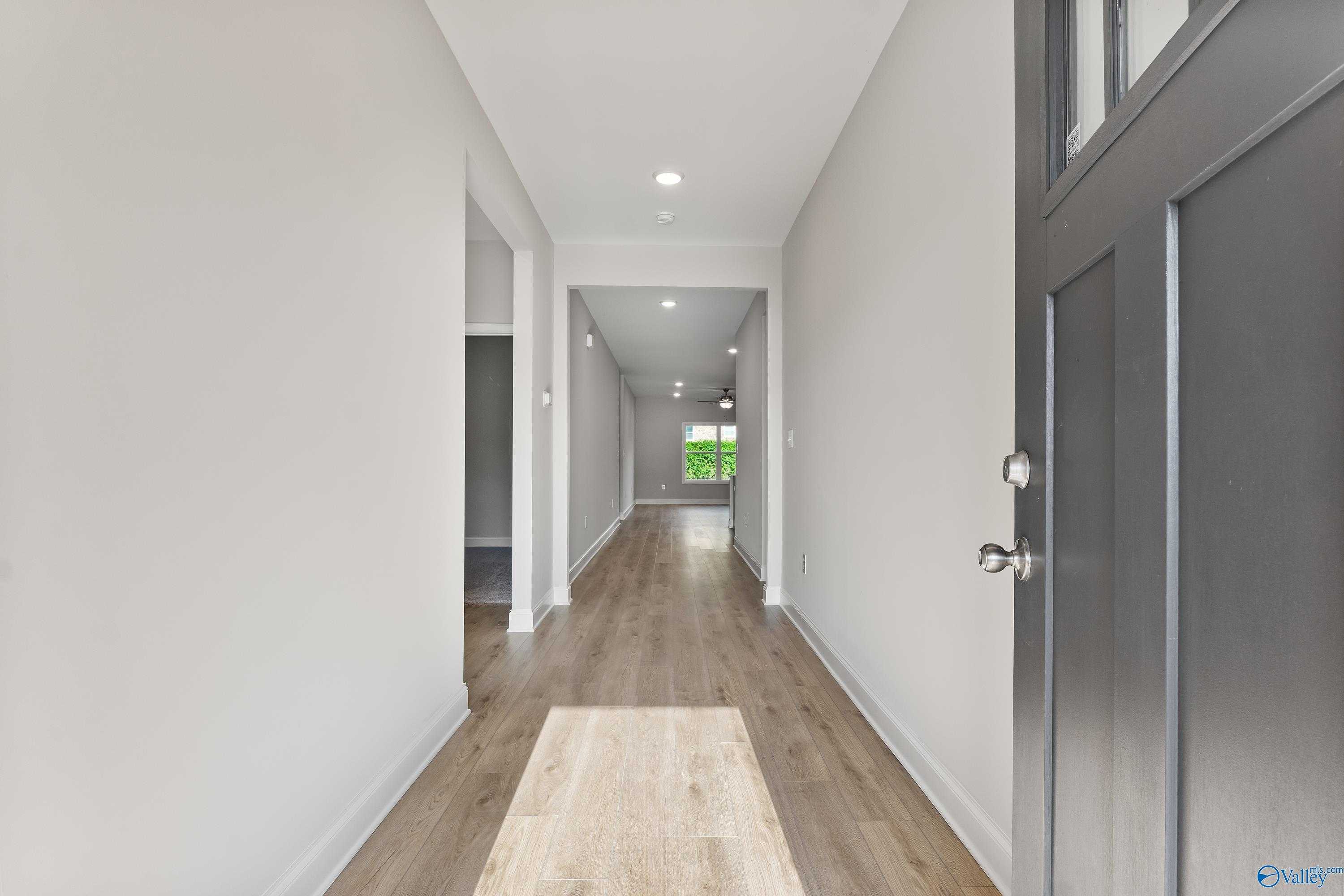 Bright hallway with light wood floors, white walls, and recessed lighting in Davidson Homes The Daphne C, Huntsville, AL