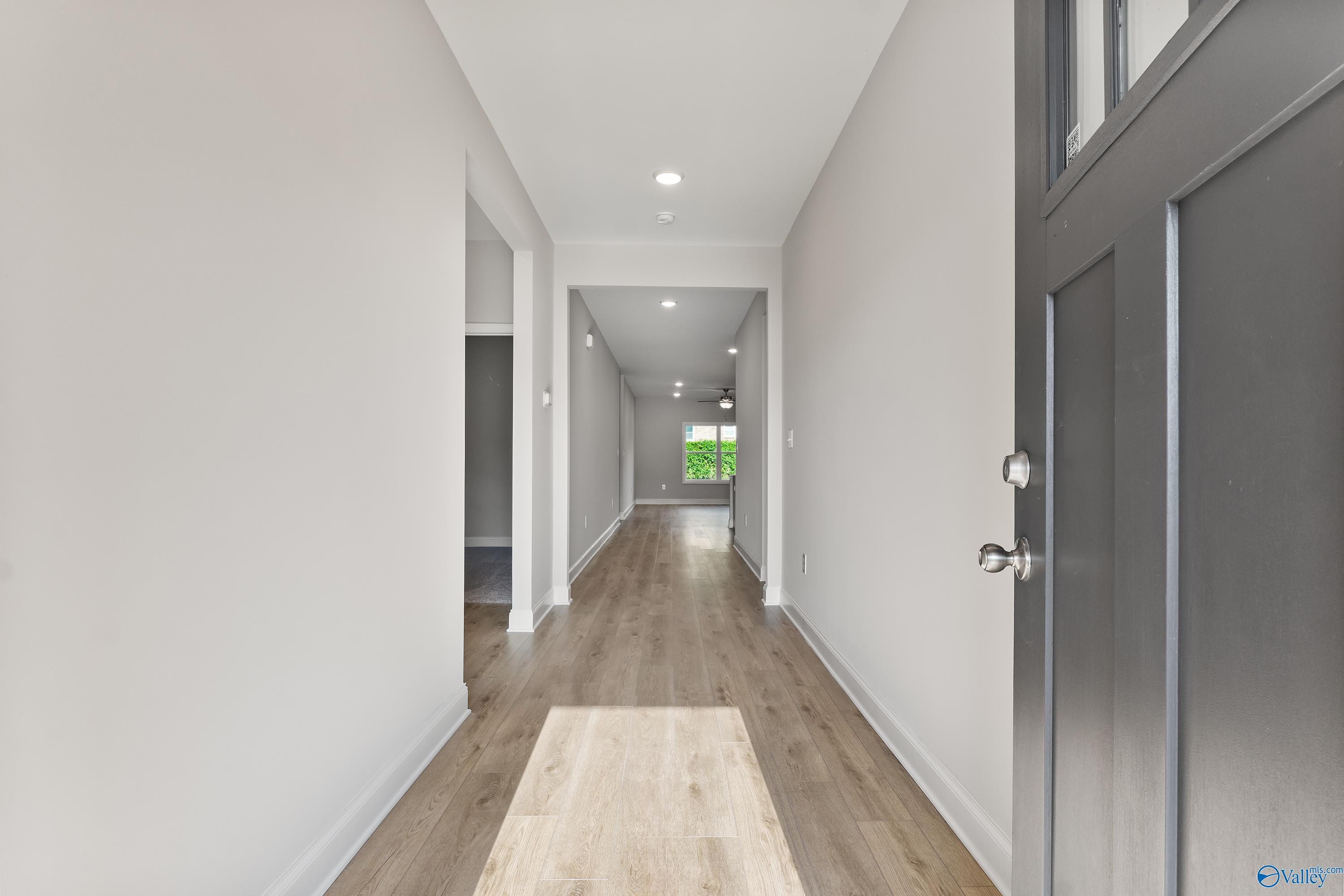 Bright hallway with light oak floors, white walls, and recessed lights in The Daphne C 4-bedroom home, Huntsville, Alabama