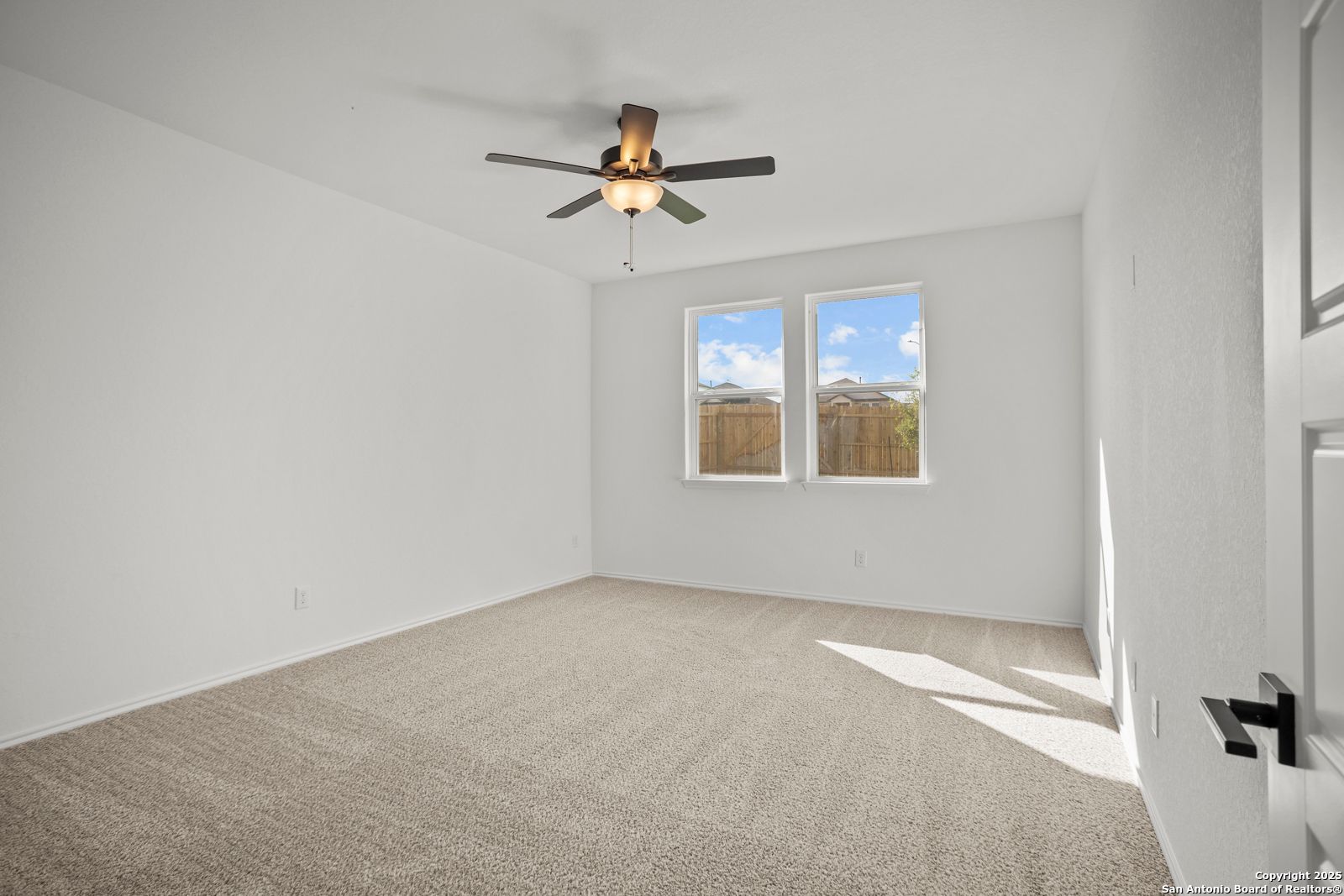 Bright bedroom with ceiling fan, large windows, beige carpet in 4-bedroom The Daphne K home, Comanche Ridge, San Antonio