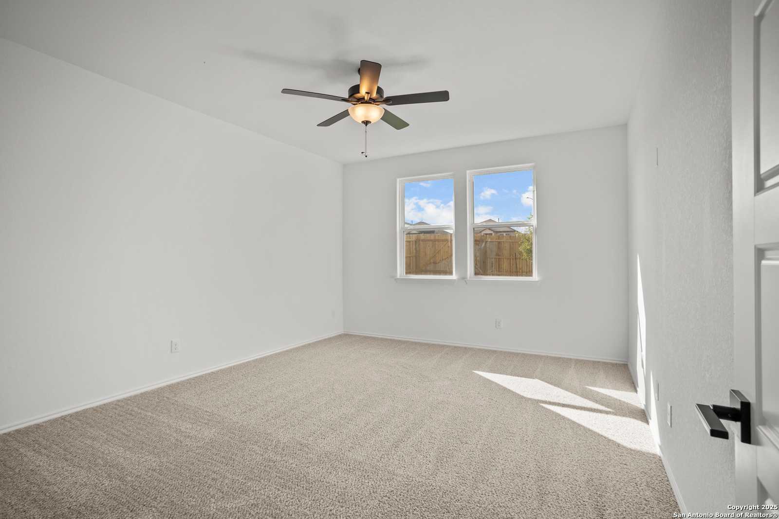 Bright bedroom with ceiling fan, large windows, beige carpet in 4-bedroom The Daphne K home, Comanche Ridge, San Antonio
