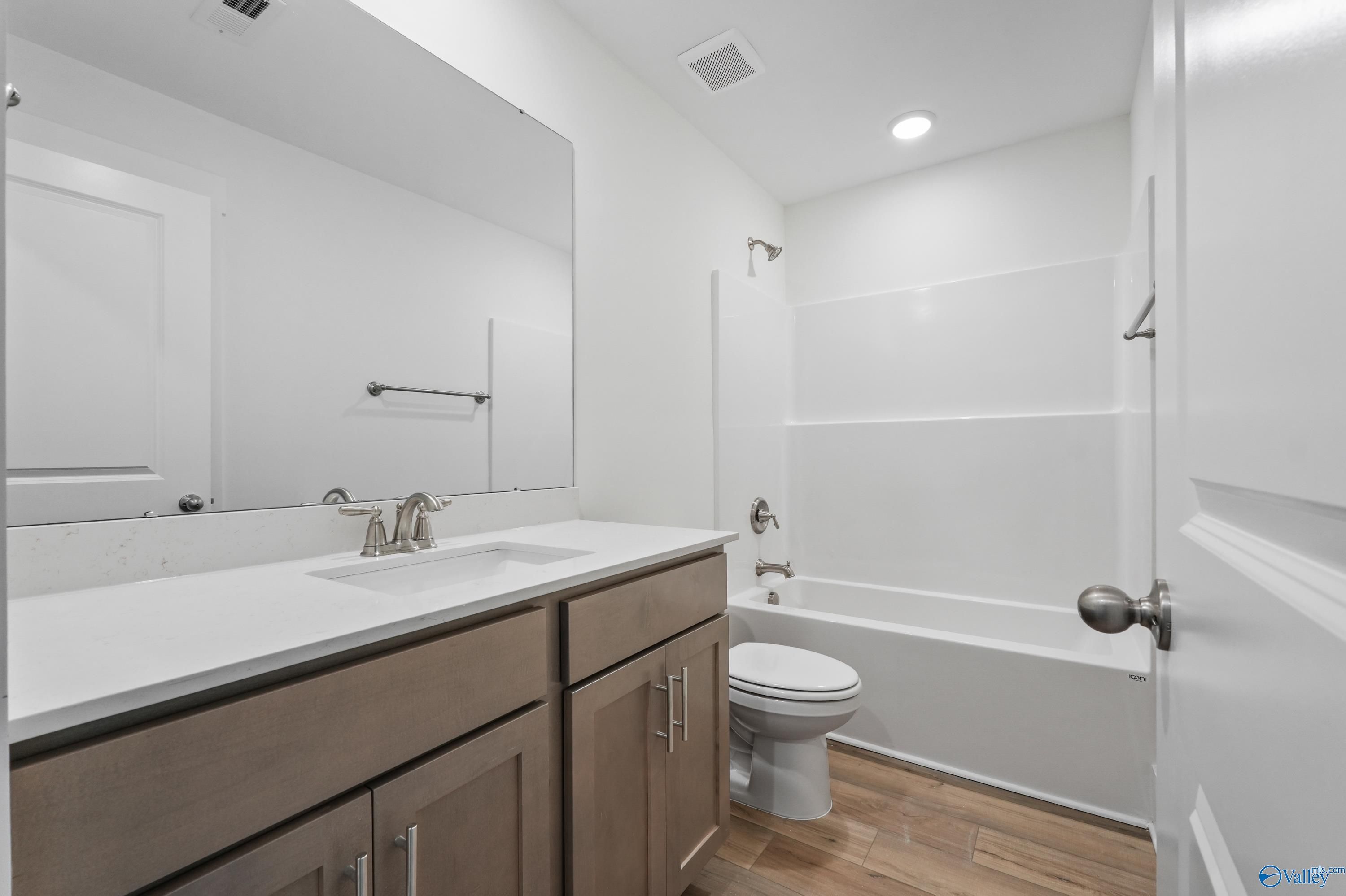 Modern master bathroom with double vanity, soaking tub, shower, and wood flooring in Davidson Homes The Daphne C, Arab, Alabama