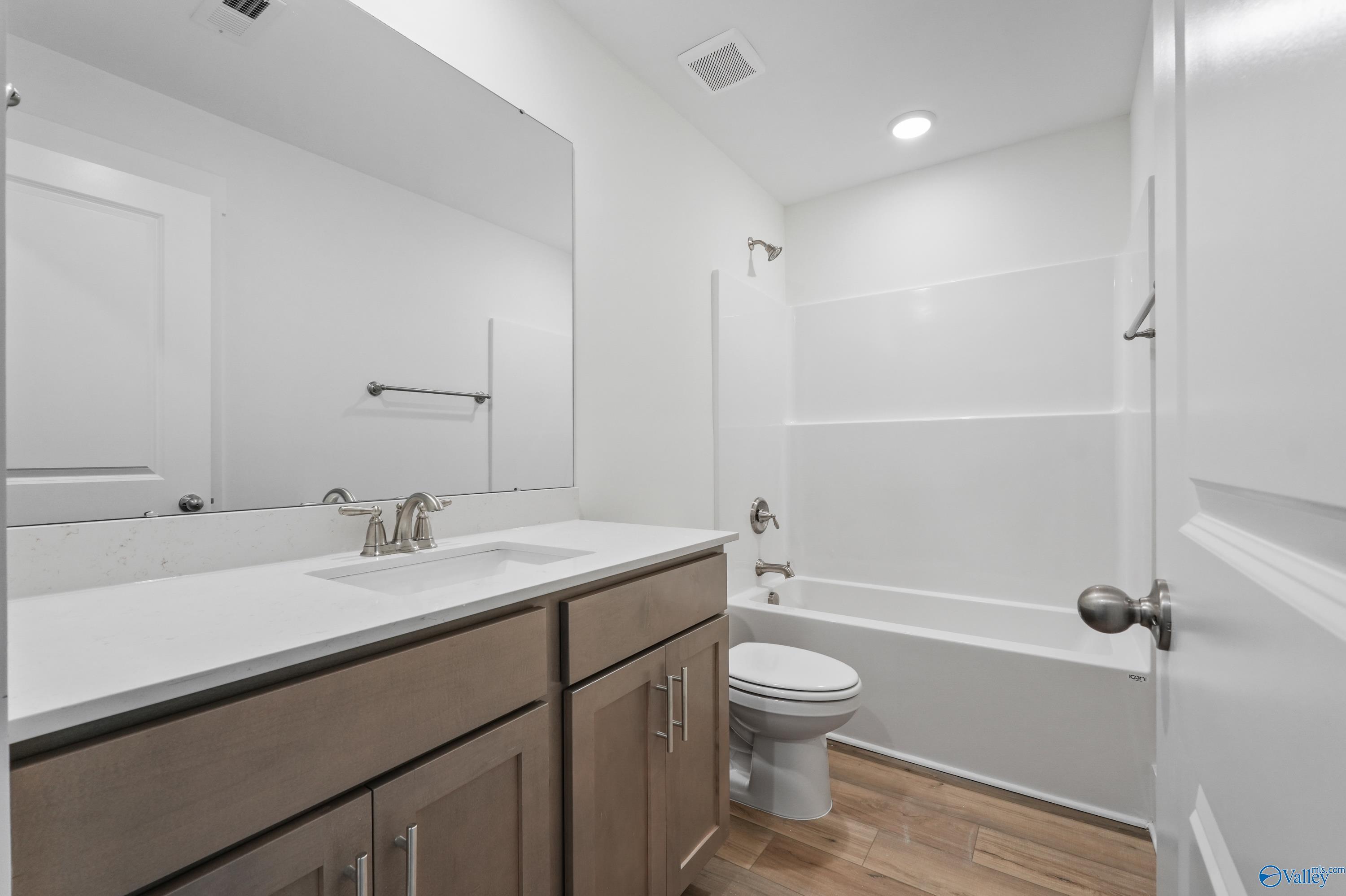 Modern double vanity bathroom with quartz counters, tub-shower combo, and wood floors in Davidson Homes The Daphne C, The Highlands, Arab, AL