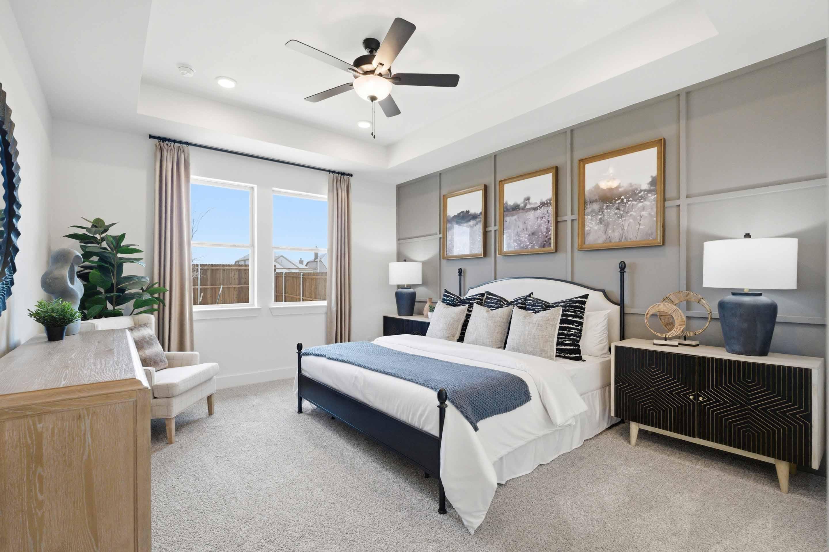 Spacious master suite in The Laurel M featuring a tray ceiling, stylish accent wall, and modern bedroom decor.