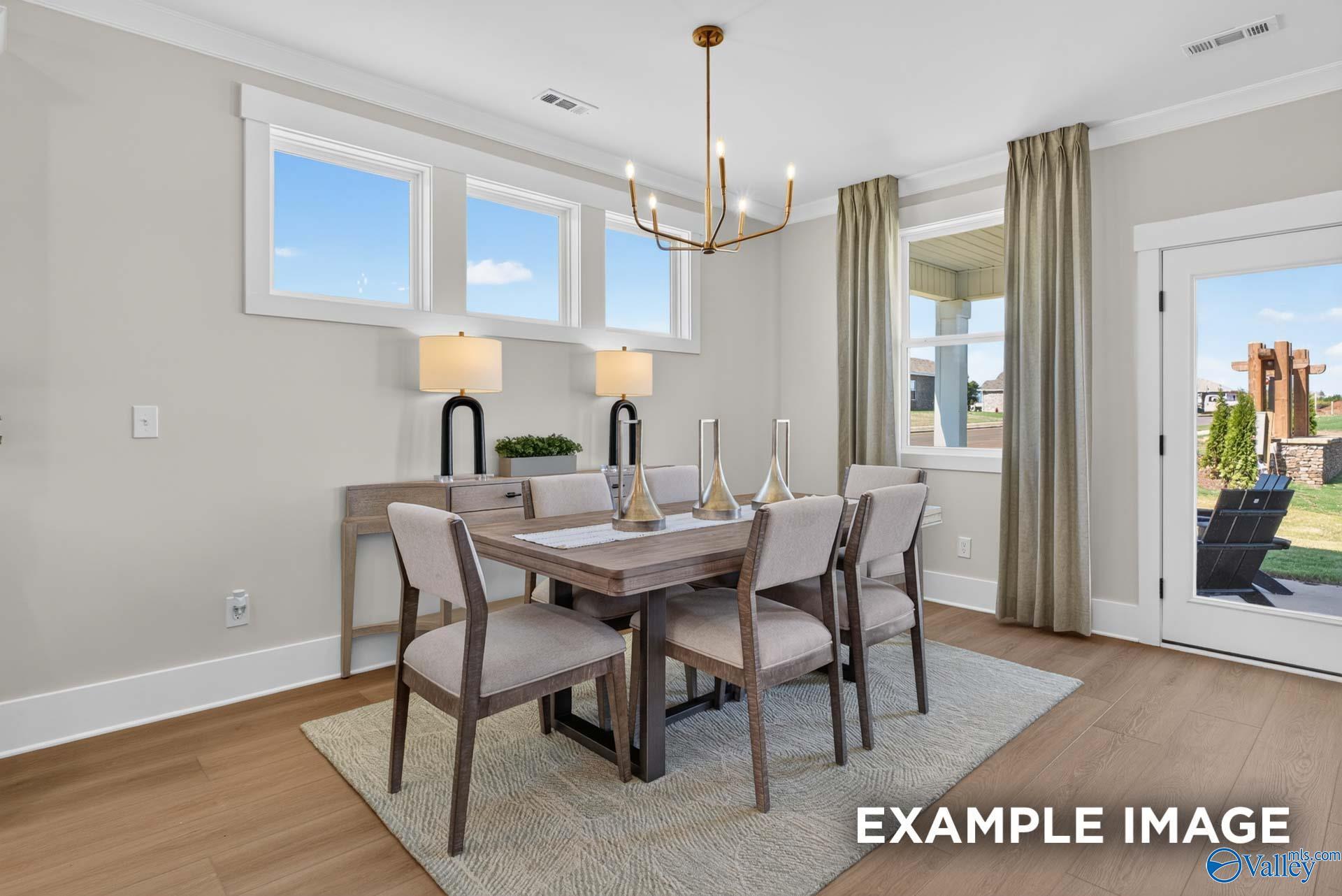 Bright dining room with wood table, upholstered chairs, and brass chandelier in Davidson Homes The Ashport K, Hazel Green, Alabama