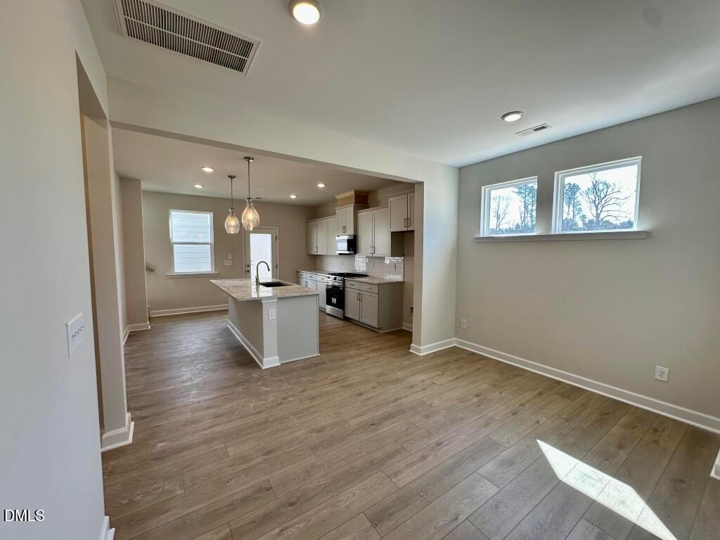 Modern open-concept kitchen with white island, recessed lights, and hardwood floors in Davidson Homes The Burke, Knightdale, NC