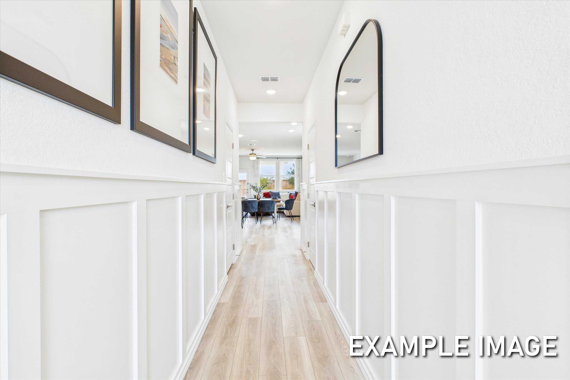 Spacious hallway in The Brazos A home featuring white wainscoting, framed art, mirrors, hardwood floors, and open living area
