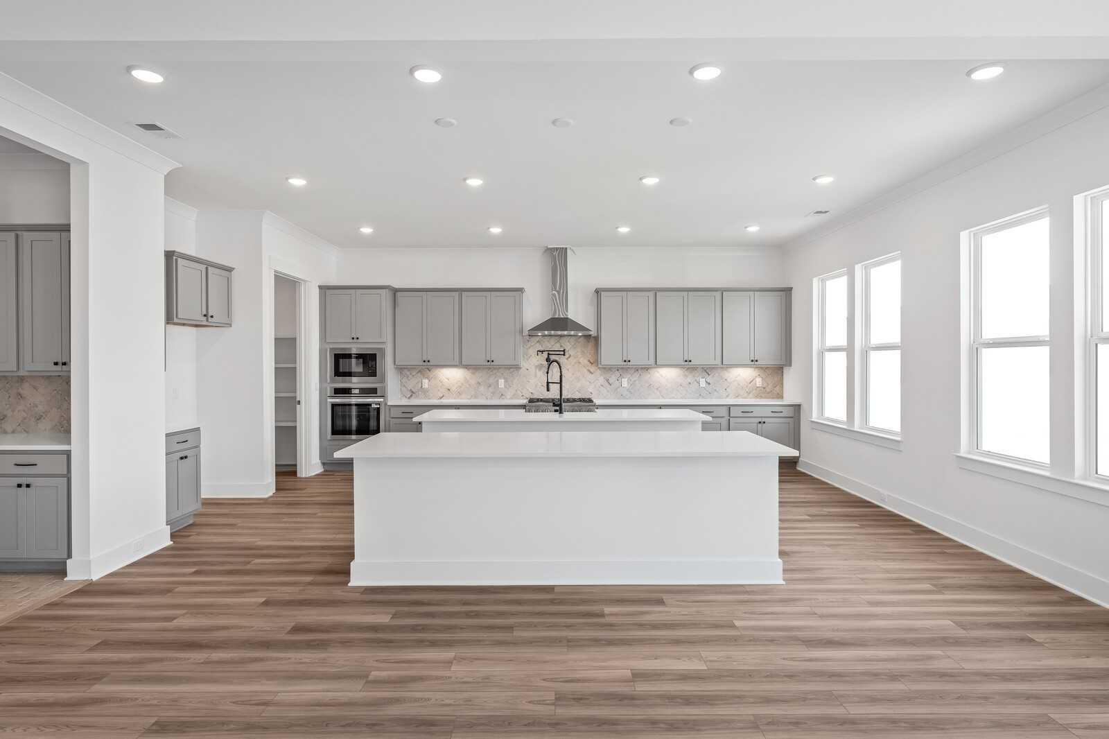 Modern open-concept kitchen featuring white island, gray shaker cabinets, stainless appliances in Davidson Homes The Alston A, Murfreesboro, TN