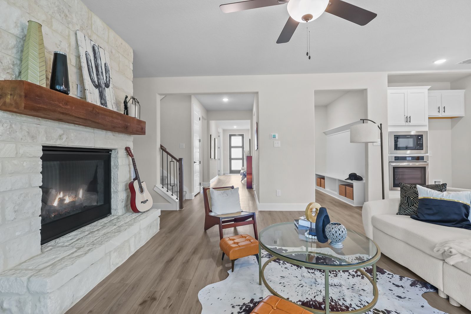 Open-concept living room in The Belmont featuring a stone fireplace, wood floors, and modern interior design.