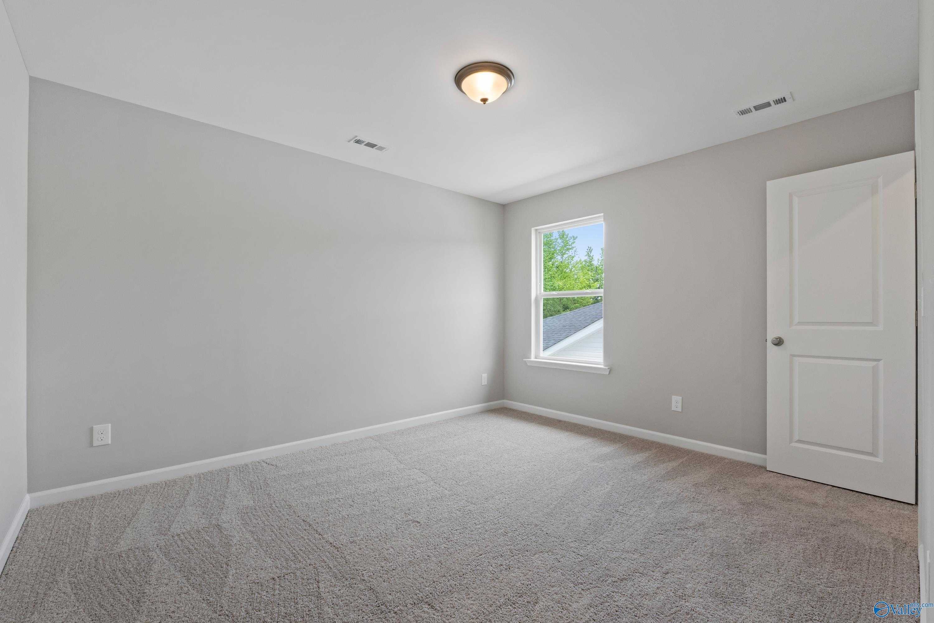 Bright secondary bedroom with light gray walls, beige carpet, and window in The Stella floor plan, Davidson Homes Hazel Green